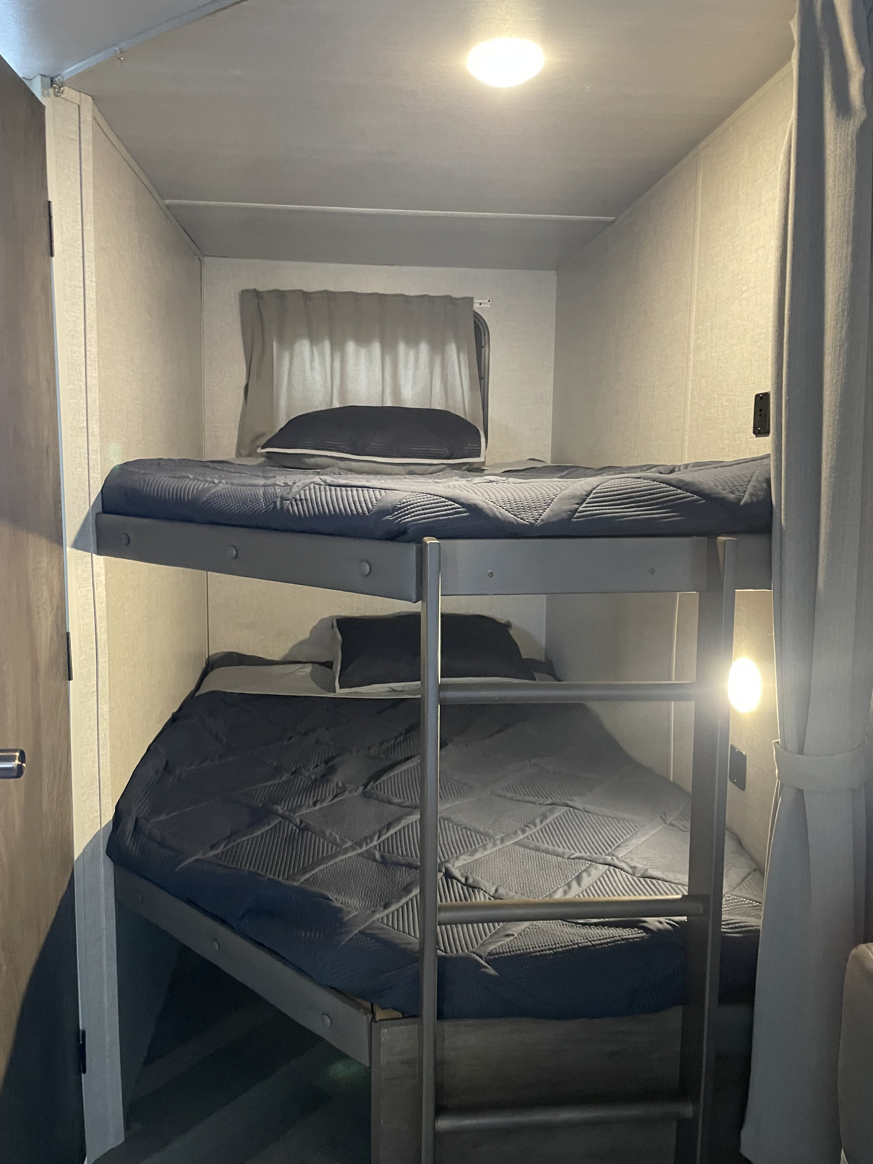 Bunk beds with dark blue bedding inside an RV rental, providing cozy sleeping quarters for your adventures.. Forest River Salem 2021
