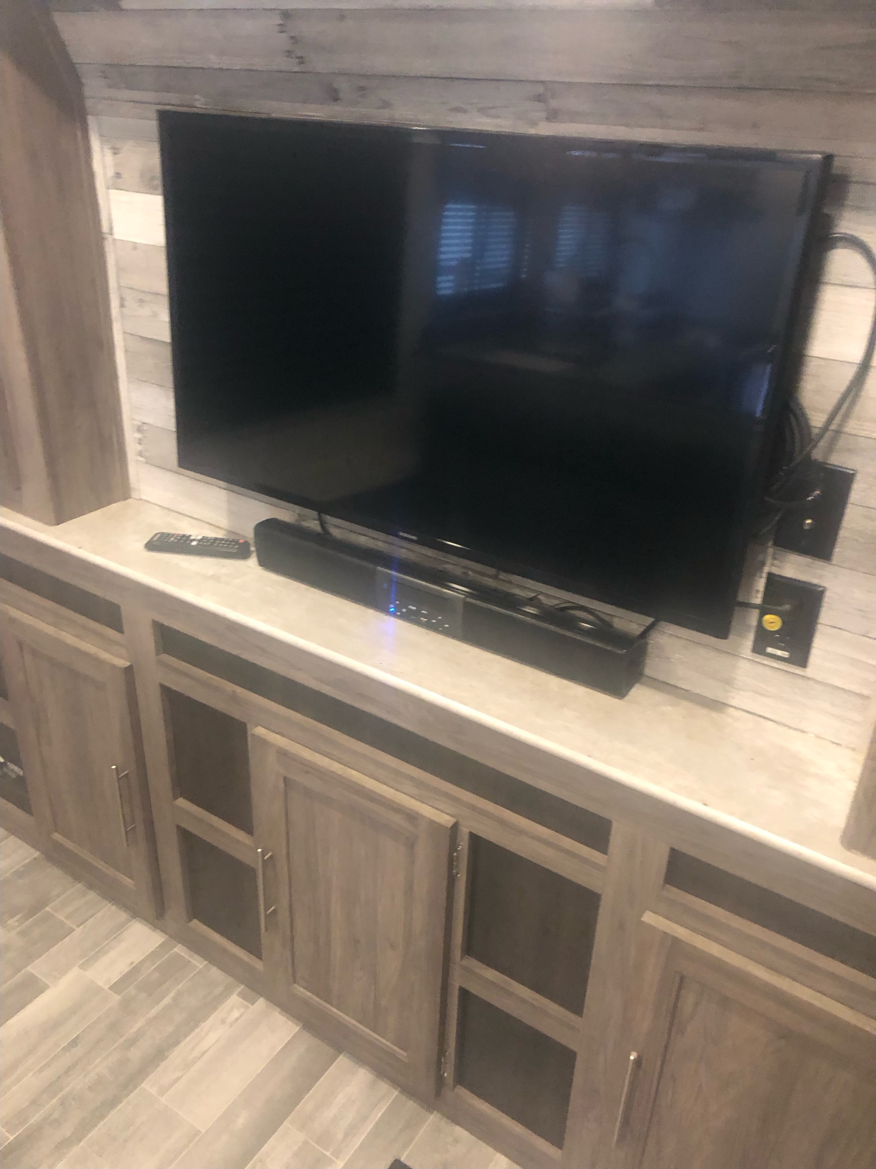 Cozy RV rental interior with TV, soundbar, remote, and light wood cabinetry for entertainment & storage.. Crossroads RV Zinger Lite 2022