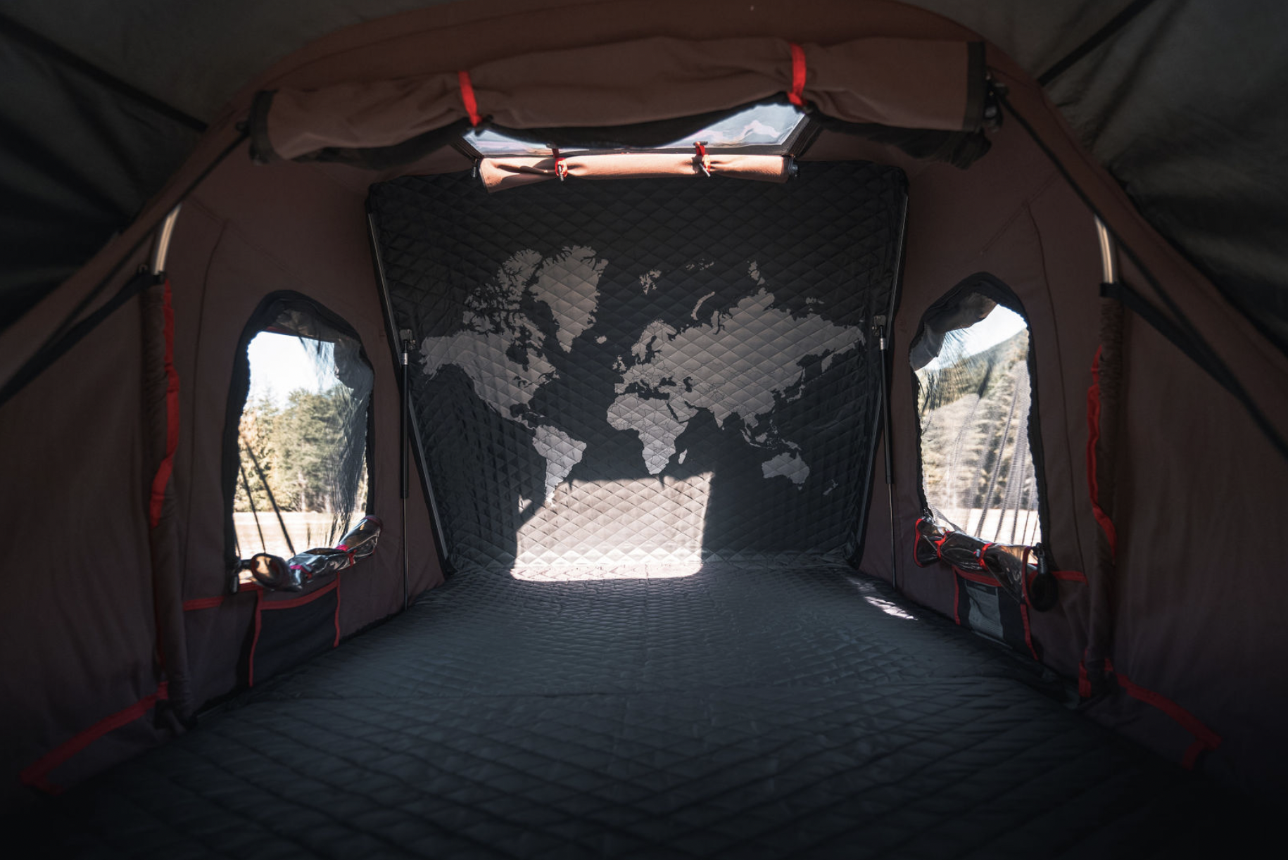 Inside a cozy **rv rental** tent: a quilted interior with a world map on the back wall and side windows showing nature.. Toyota Tacoma 2023