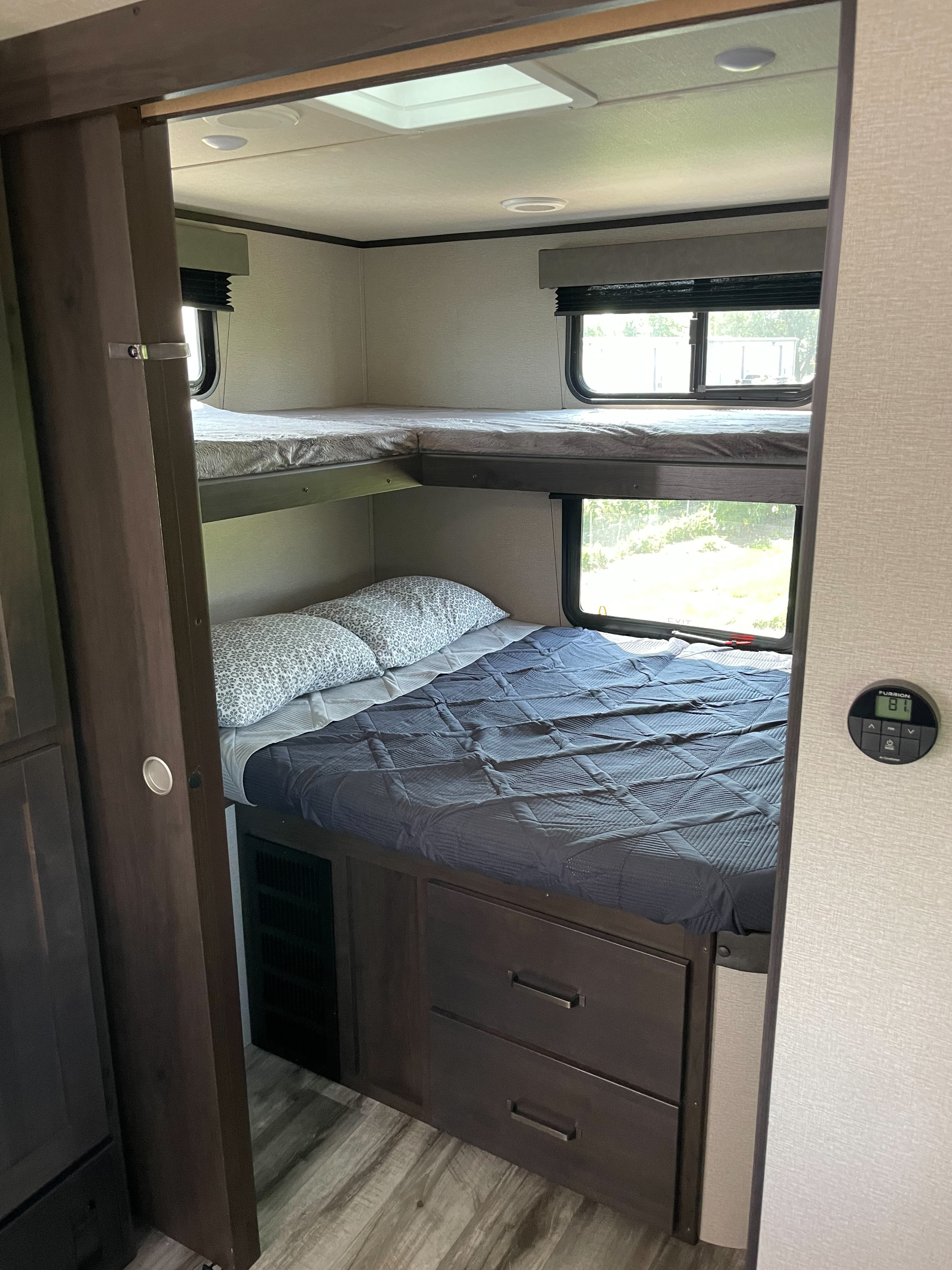 This RV rental interior features cozy bunk beds with windows, under-bed storage, and a thermostat. Ideal for family adventures.. Grand Design Transcend Xplor 2023