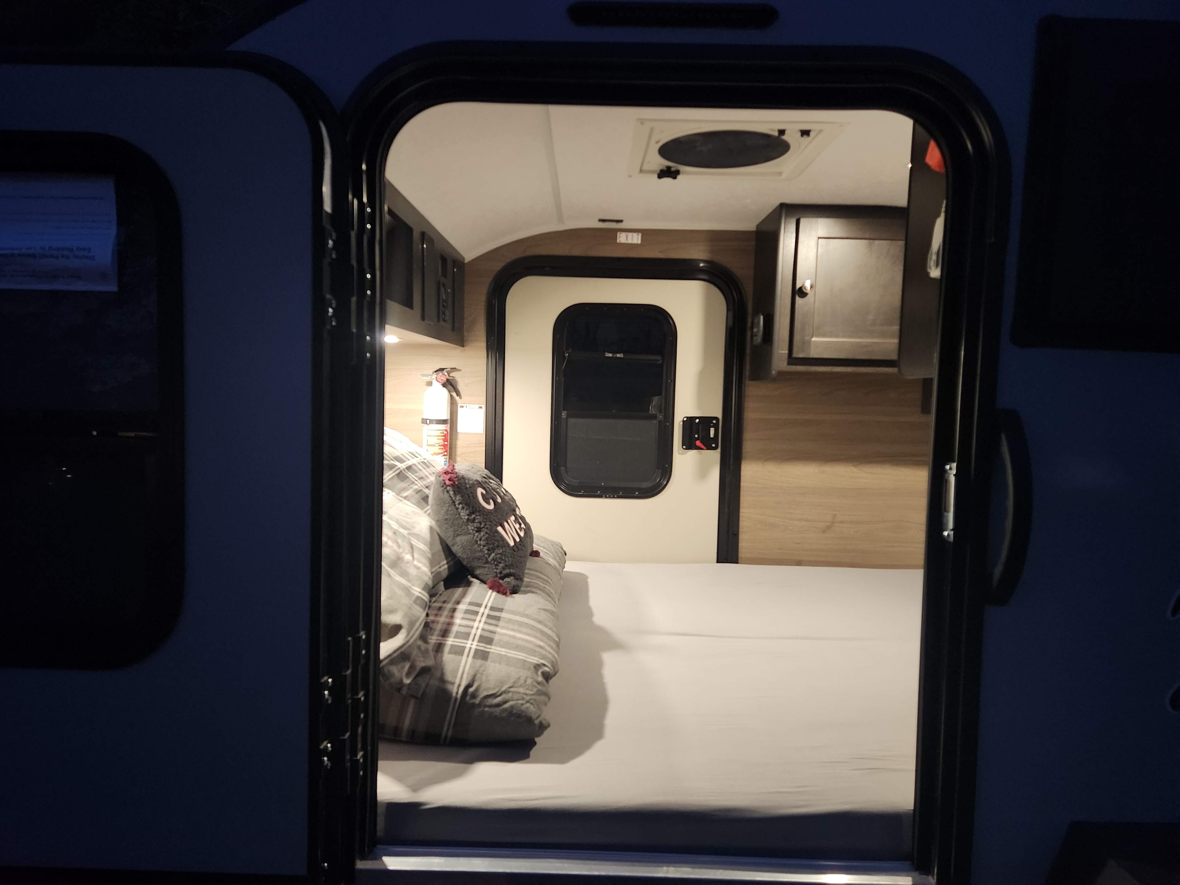 Step into this cozy RV rental: compact interior features a made bed, storage, and visible fire extinguisher for safety.. Braxton Creek Bushwacker 2023