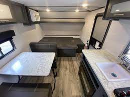 Compact RV rental interior featuring a dinette, convertible bed, and kitchen. Ideal for adventure!. Aspen Trail LE 2023