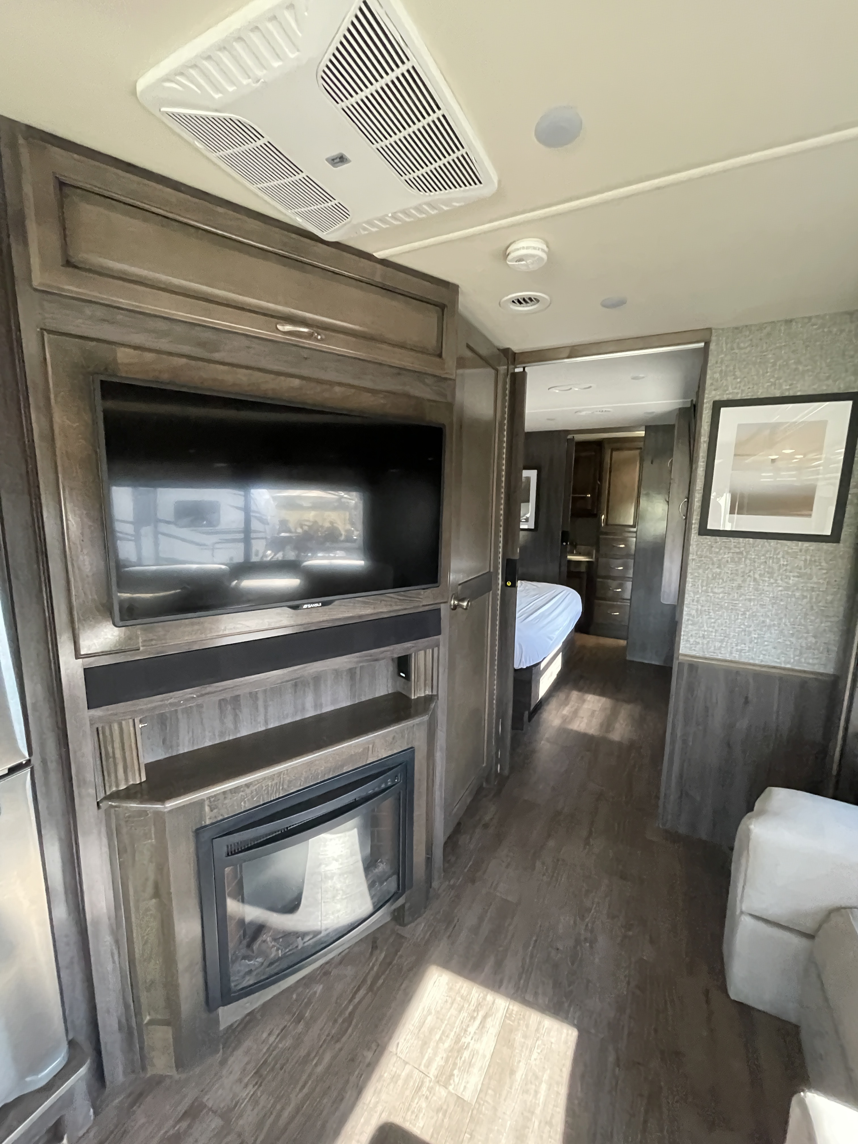 Modern RV rental interior with TV, fireplace, and bedroom view, ideal for travel comfort.. Fleetwood Bounder 2018