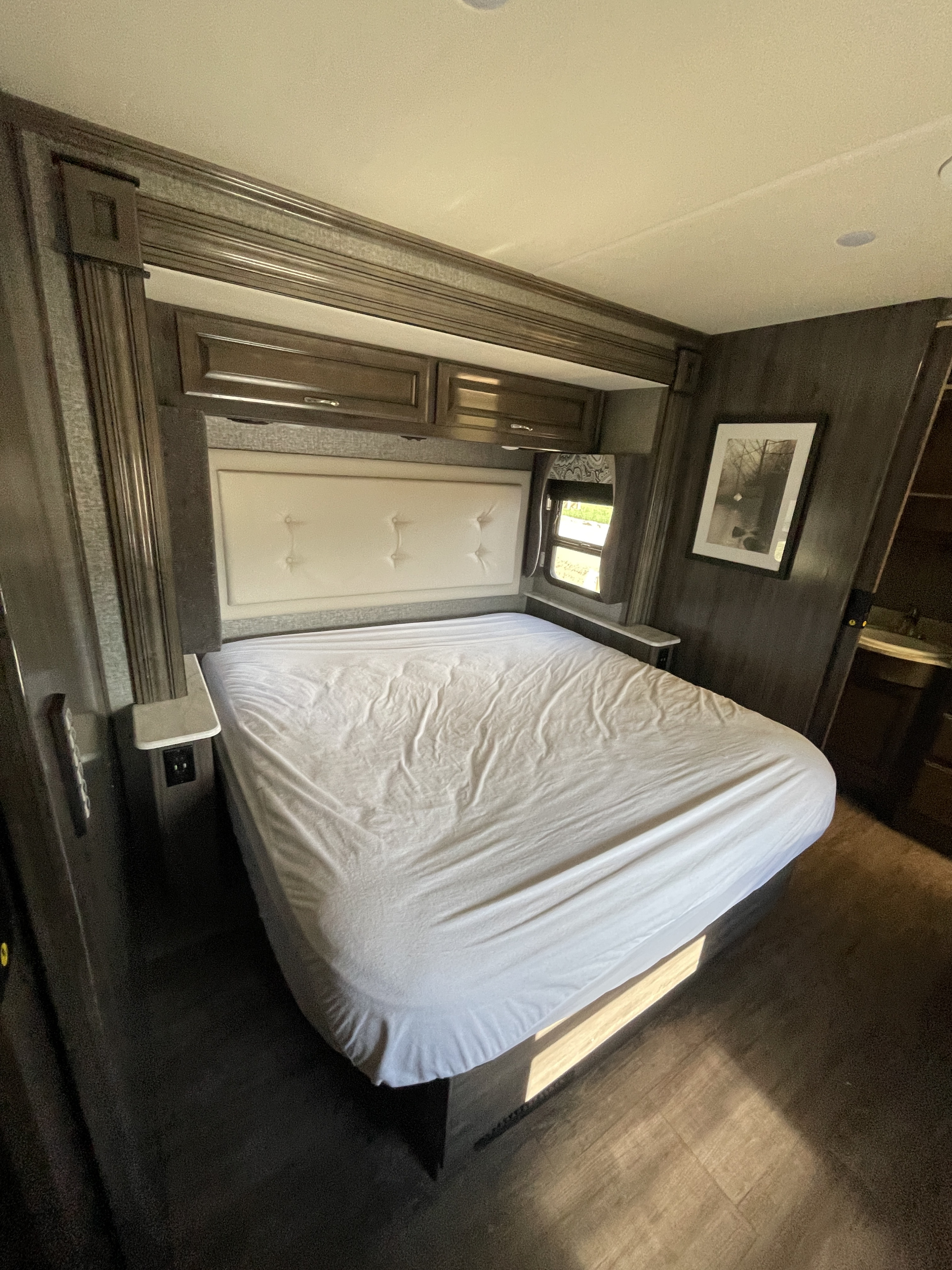 Spacious RV bedroom with a comfy bed, overhead cabinets, and wood flooring, perfect for an RV rental adventure.. Fleetwood Bounder 2018