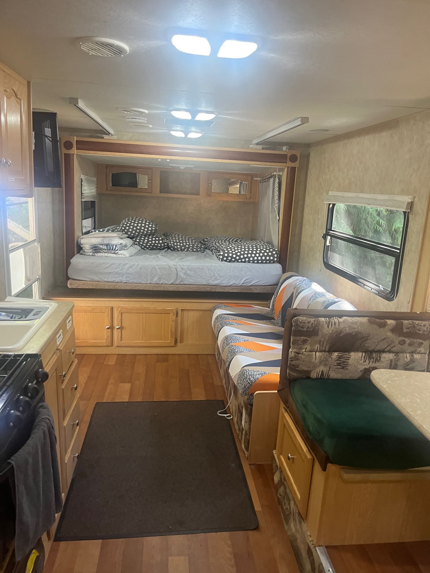 Cozy RV rental interior showcasing a comfortable bed, dinette, and compact kitchen. Ideal for road trip adventures.. Spree Spree Trailer 2008