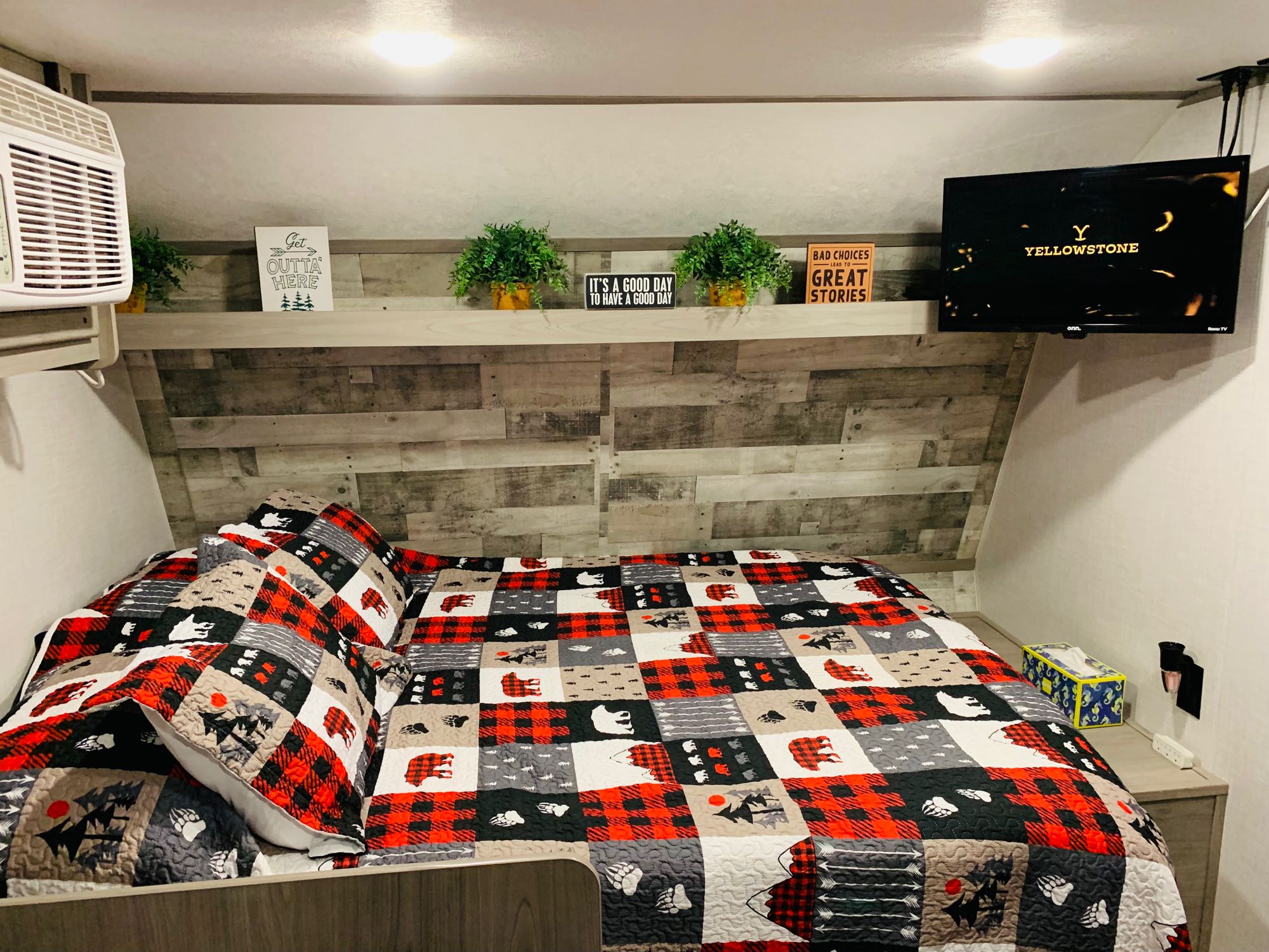 Cozy RV rental bedroom with rustic, nature-themed decor, including a quilt, signs, and a TV showing Yellowstone.. Dutchmen Coleman Lantern LT 2023