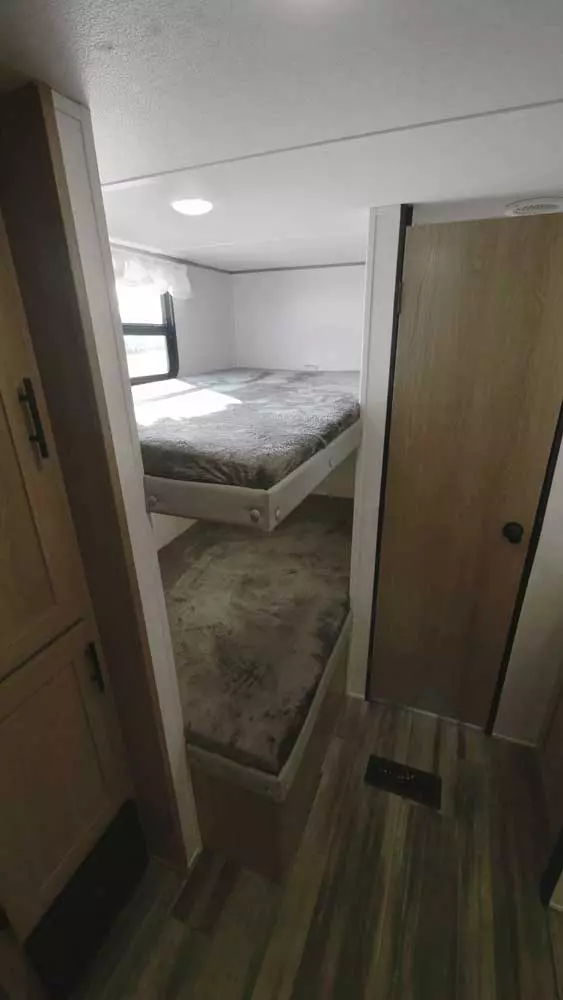 Explore this RV rental's cozy interior, featuring built-in bunk beds and wood flooring. Ideal for a comfortable trip.. Avenger LT 2022