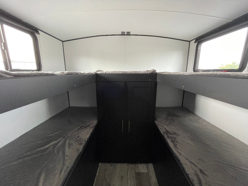 An rv rental's interior: four gray bunk beds with a central black storage cabinet & windows. Perfect camper setup.. Keystone RV Springdale 2021