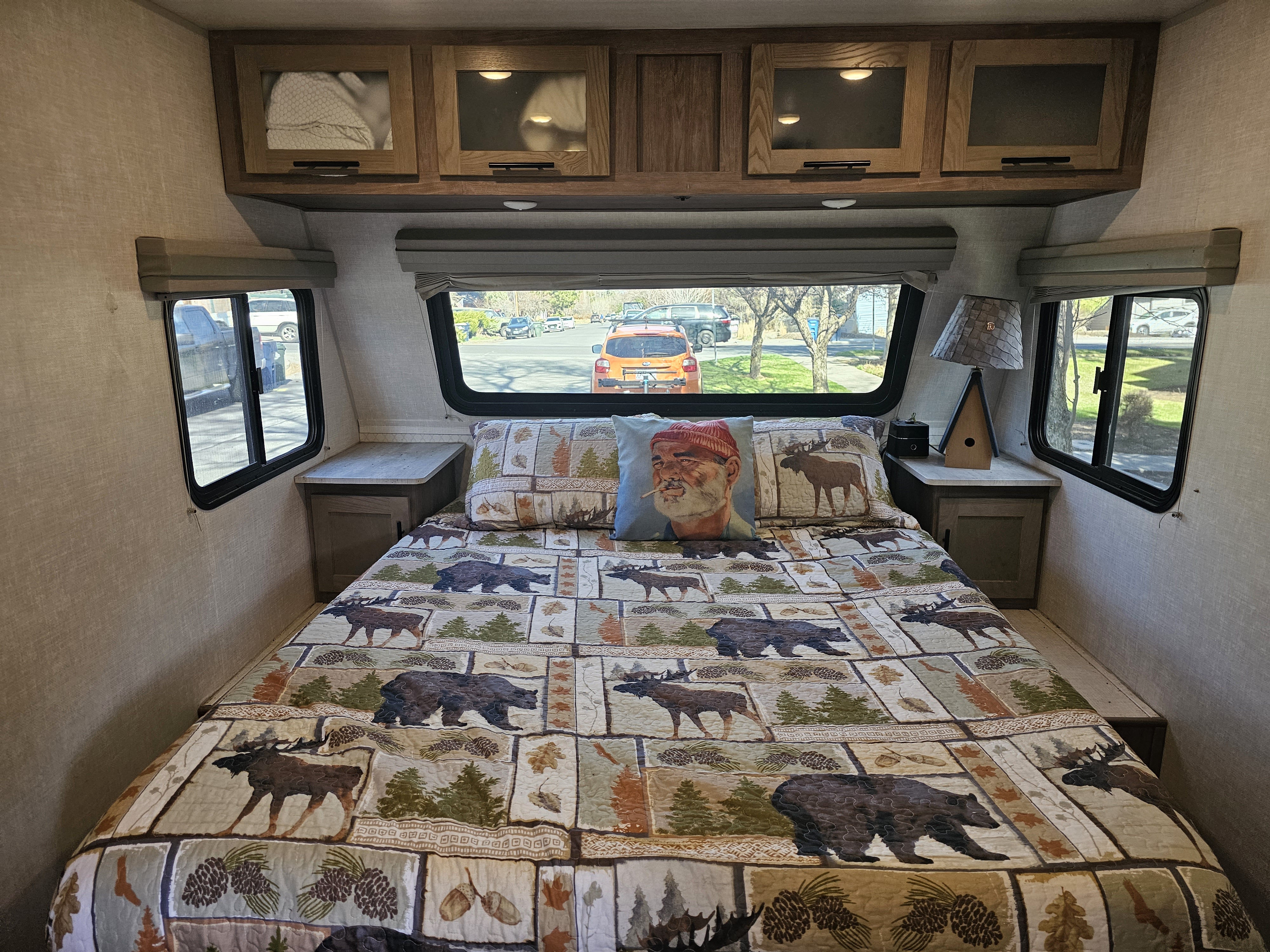 Step into comfort in this RV rental bedroom with a cozy nature-themed bed, Bill Murray pillow, and overhead storage.. No Boundaries 19 2021