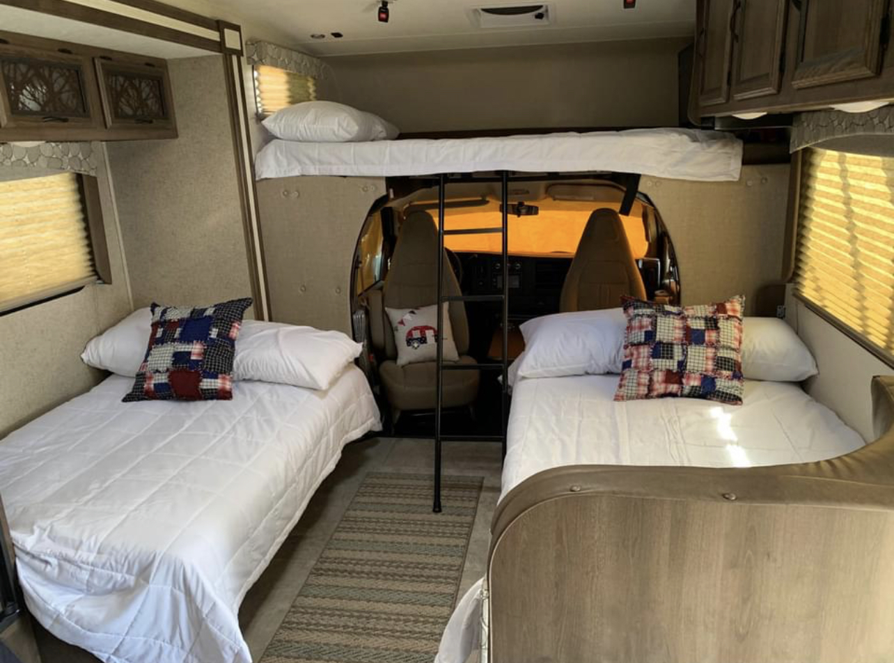 Spacious RV rental interior featuring comfortable bunk beds over the cab and two twin beds, perfect for family travel.. Chevy 4500 2019