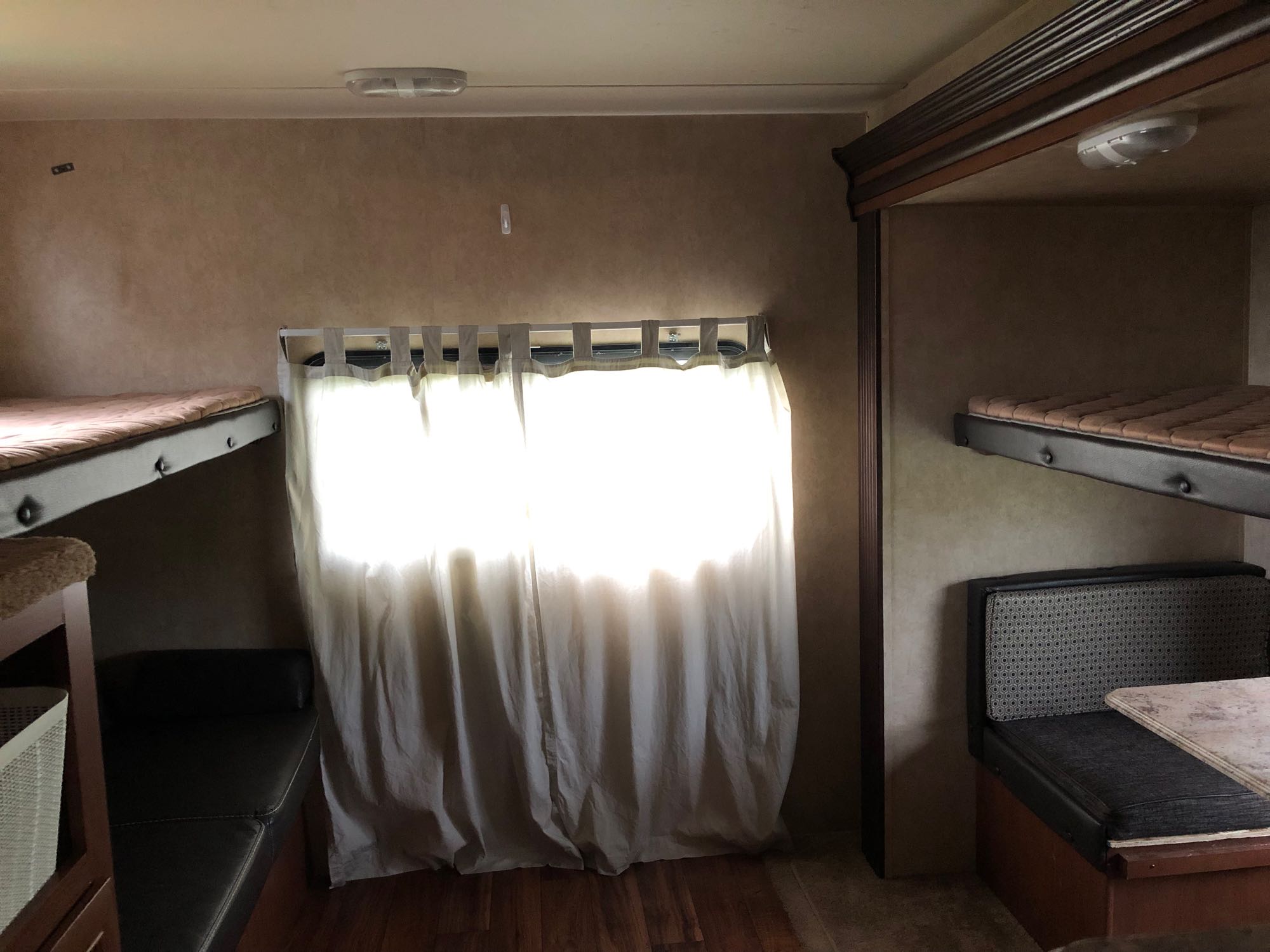RV rental's bunkhouse with multiple beds, a sunlit window with curtains, and a convertible dinette area.. Forest River Salem 2016