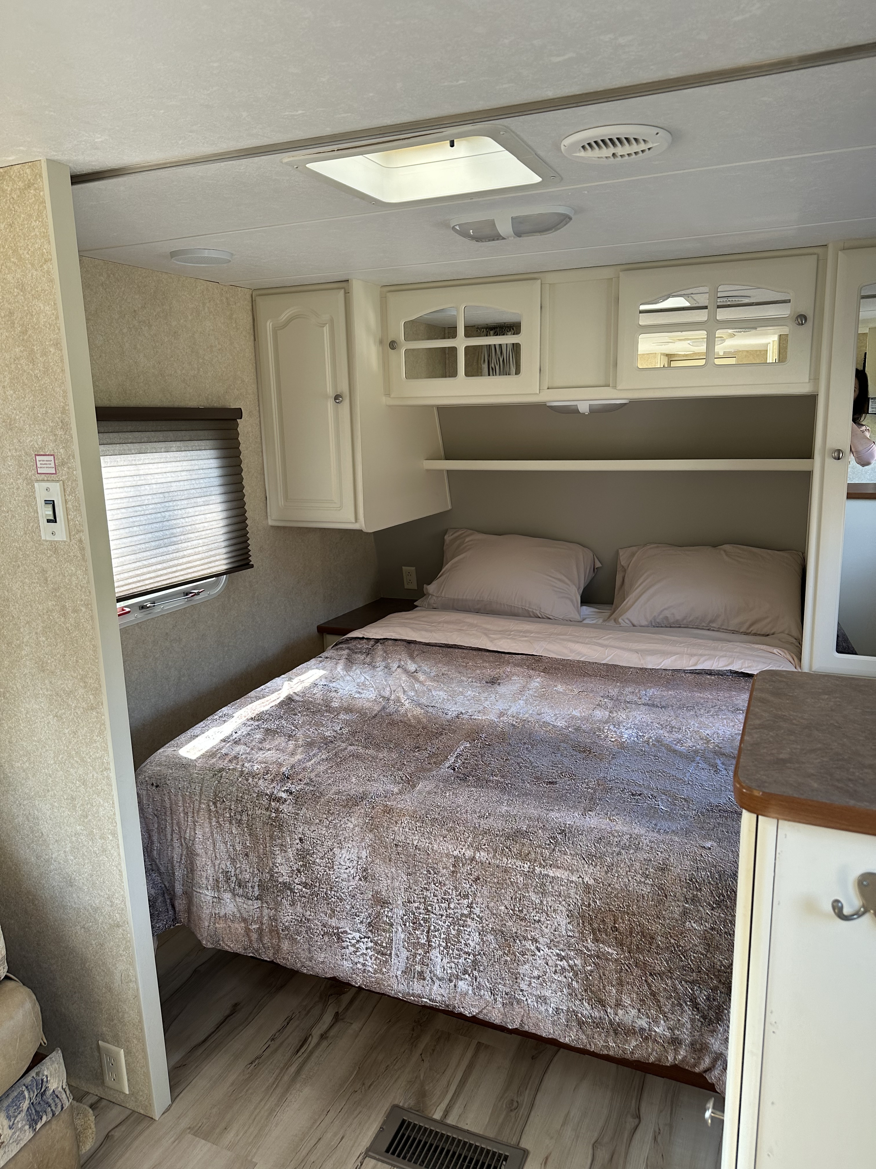 Comfortable RV rental bedroom featuring a spacious bed, overhead storage, and a bright window.. Keystone RV Outback 2005