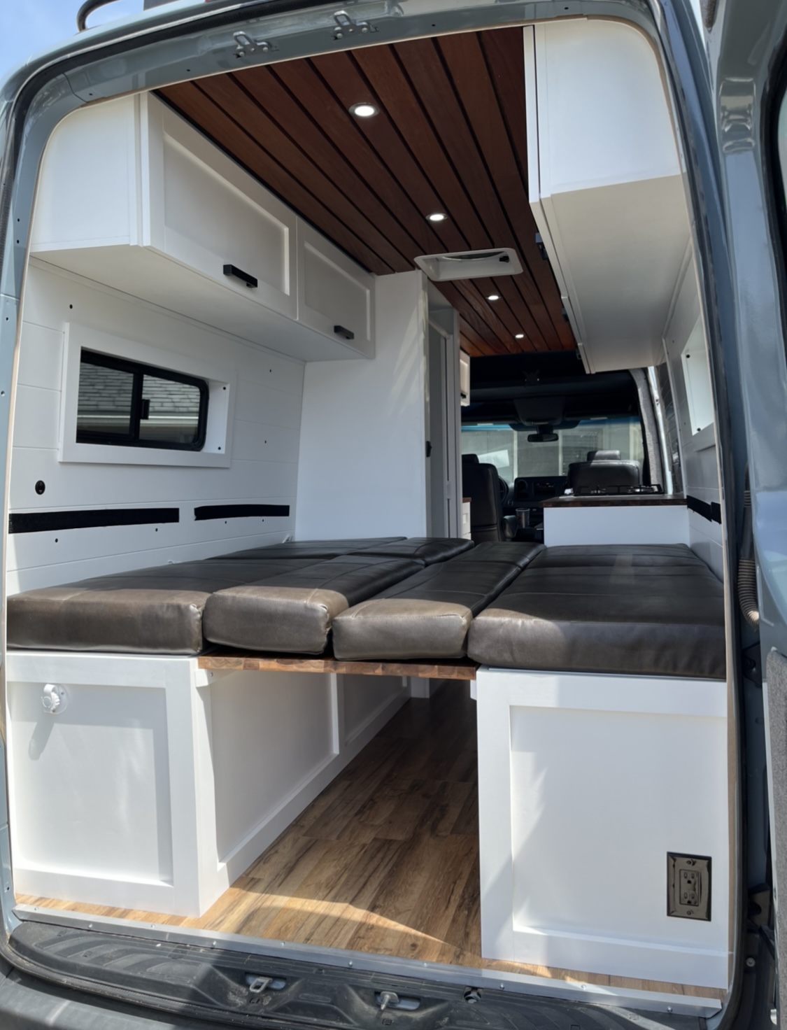 RV rental interior shows sleek wooden ceiling, white cabinets, and versatile modular bed/seating.. Mercedes Sprinter 2019