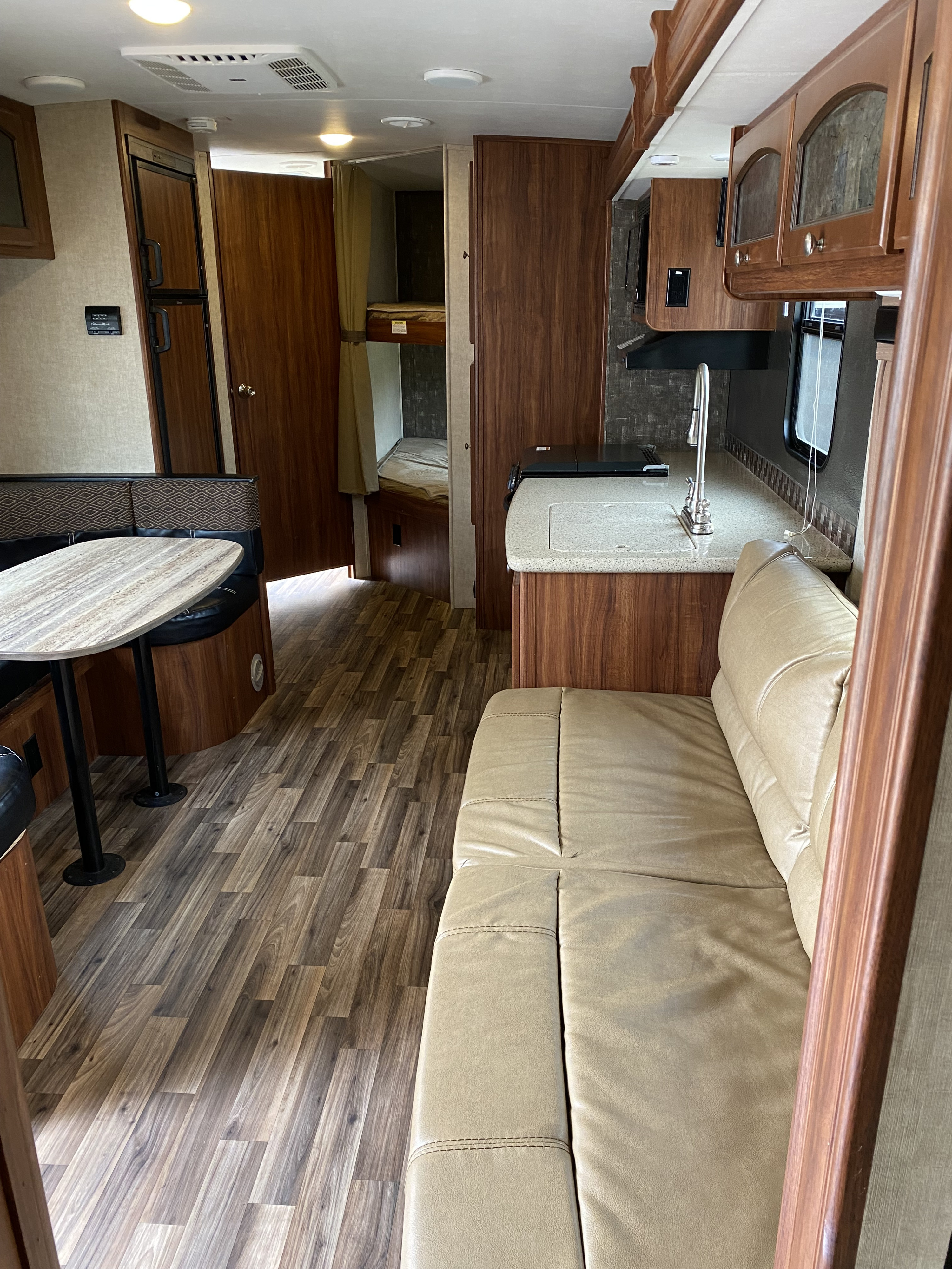 RV rental interior showcasing a full kitchen, dining area, comfortable sofa, and private bunk beds. Ready for your adventure.. Heartland RVs North Trail 2016