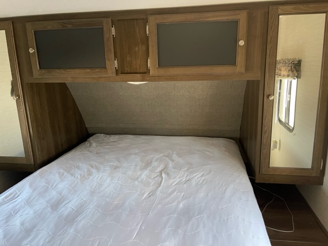 RV rental bedroom with a comfy bed, overhead cabinets, and mirrored wardrobes for compact travel lodging.. Keystone RV Bullet Ultra Lite 2018