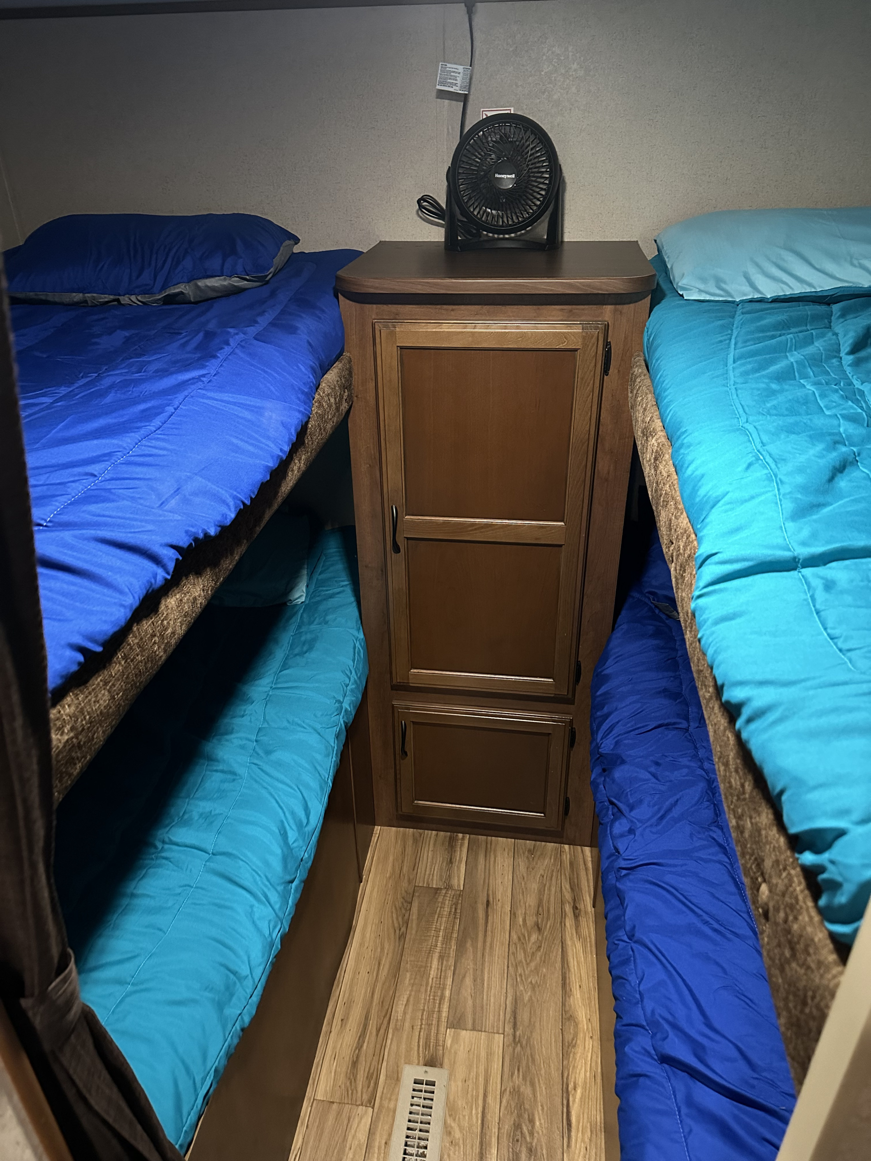 RV rental bunk beds: two sets with blue bedding, a central cabinet with a fan, and wood floors. A compact sleeping area.. Jayco Jay Flight 2016