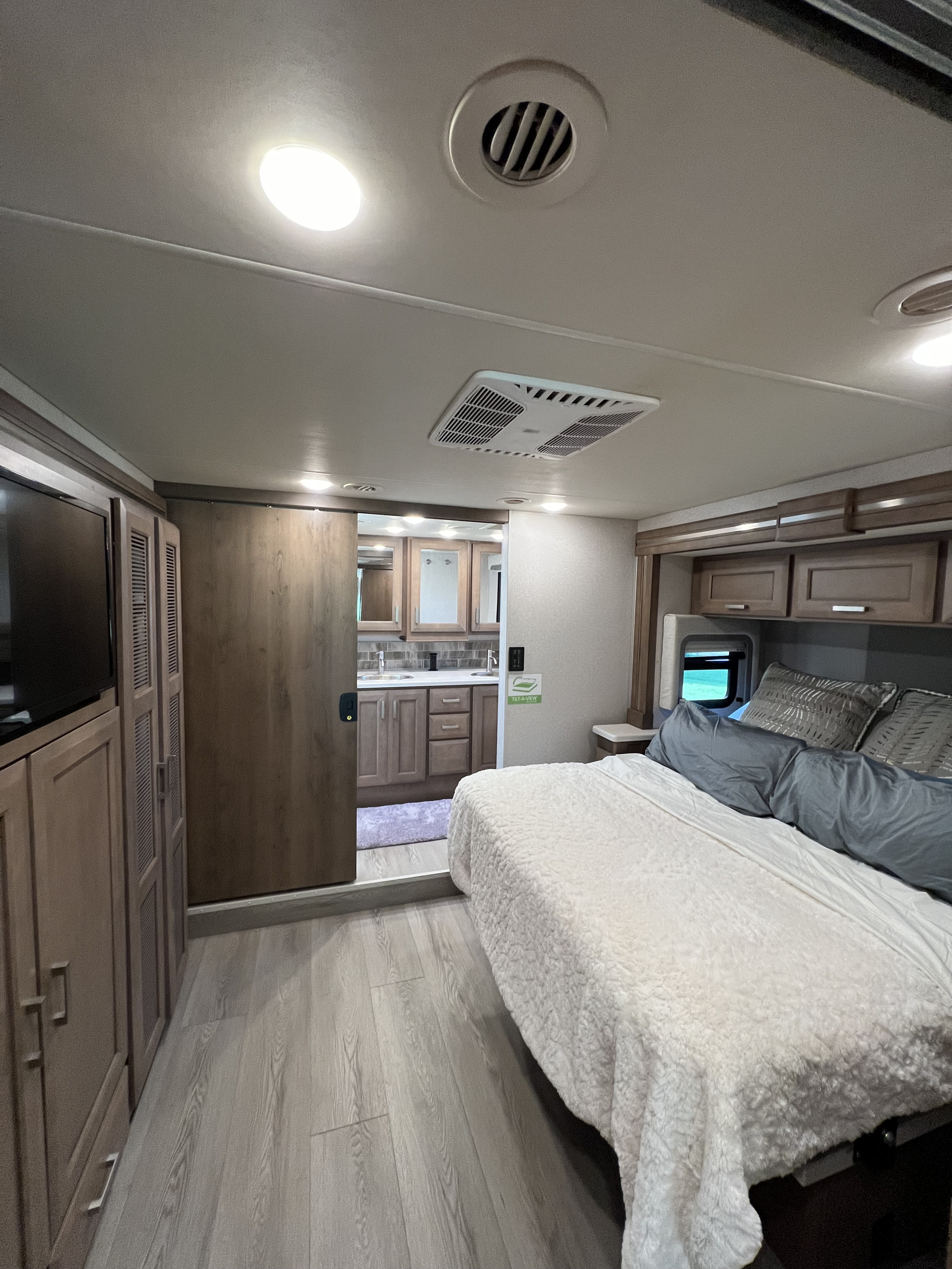 RV rental bedroom with en-suite bath, featuring a comfortable bed, TV, and modern decor for a relaxing stay.. Thor Palazzo 2023