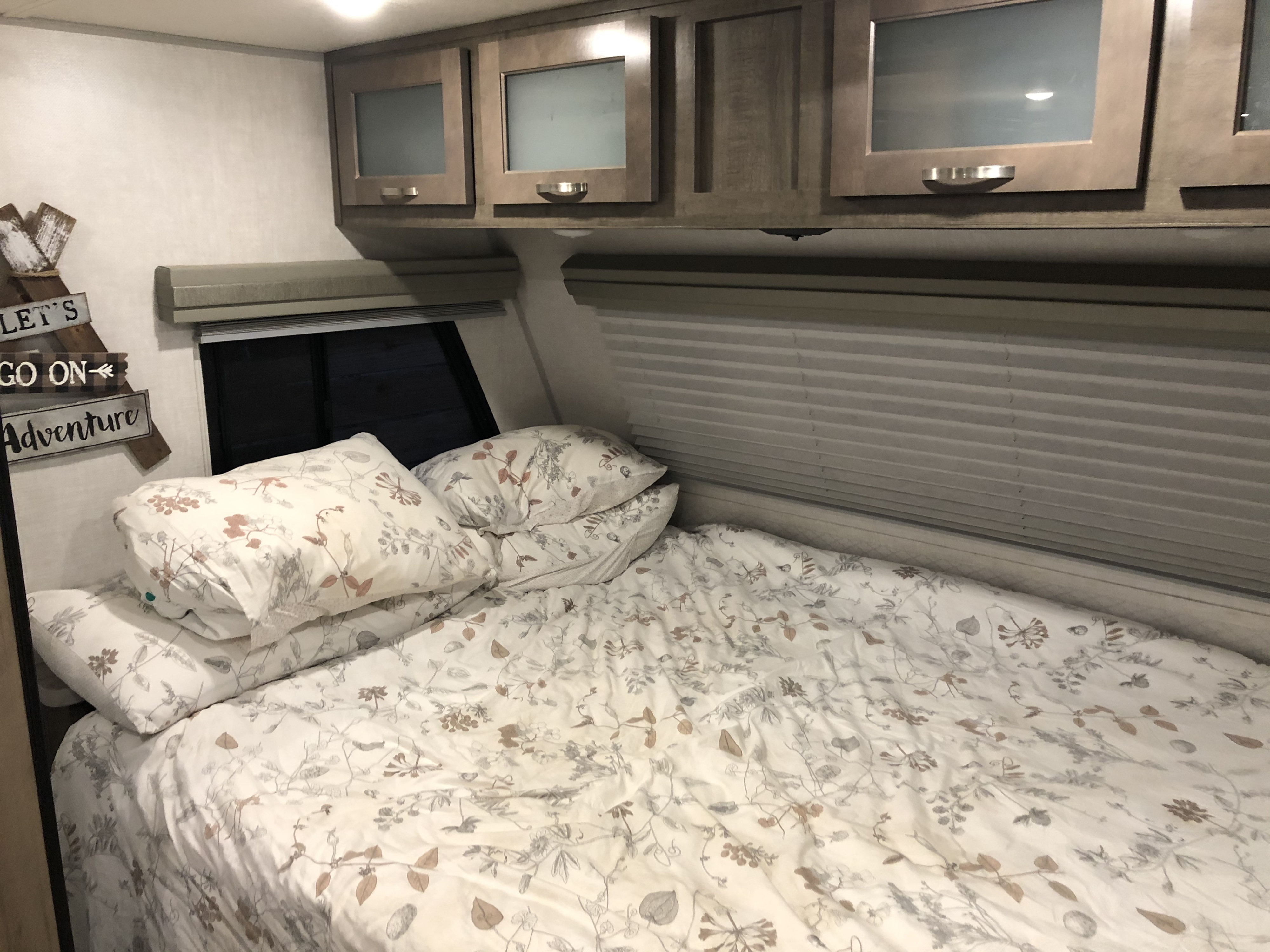 Cozy RV rental bedroom with patterned bedding, overhead cabinets, and windows. Perfect for your next adventure.. No Boundaries 19 2020