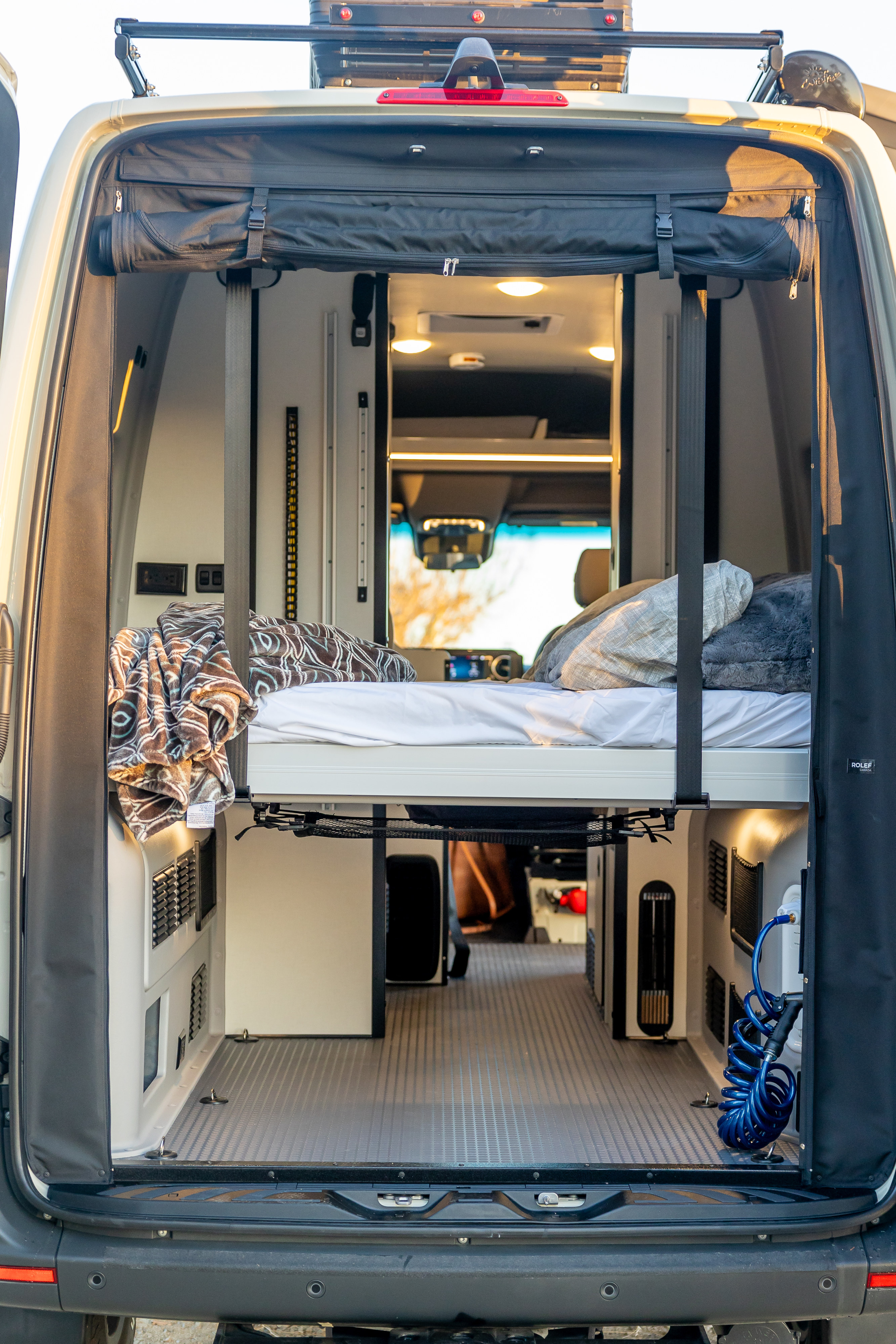 Inside a versatile RV rental camper van with an elevated bed, ample storage, and utility access. Ready for adventure!. Winnebago Revel 2023