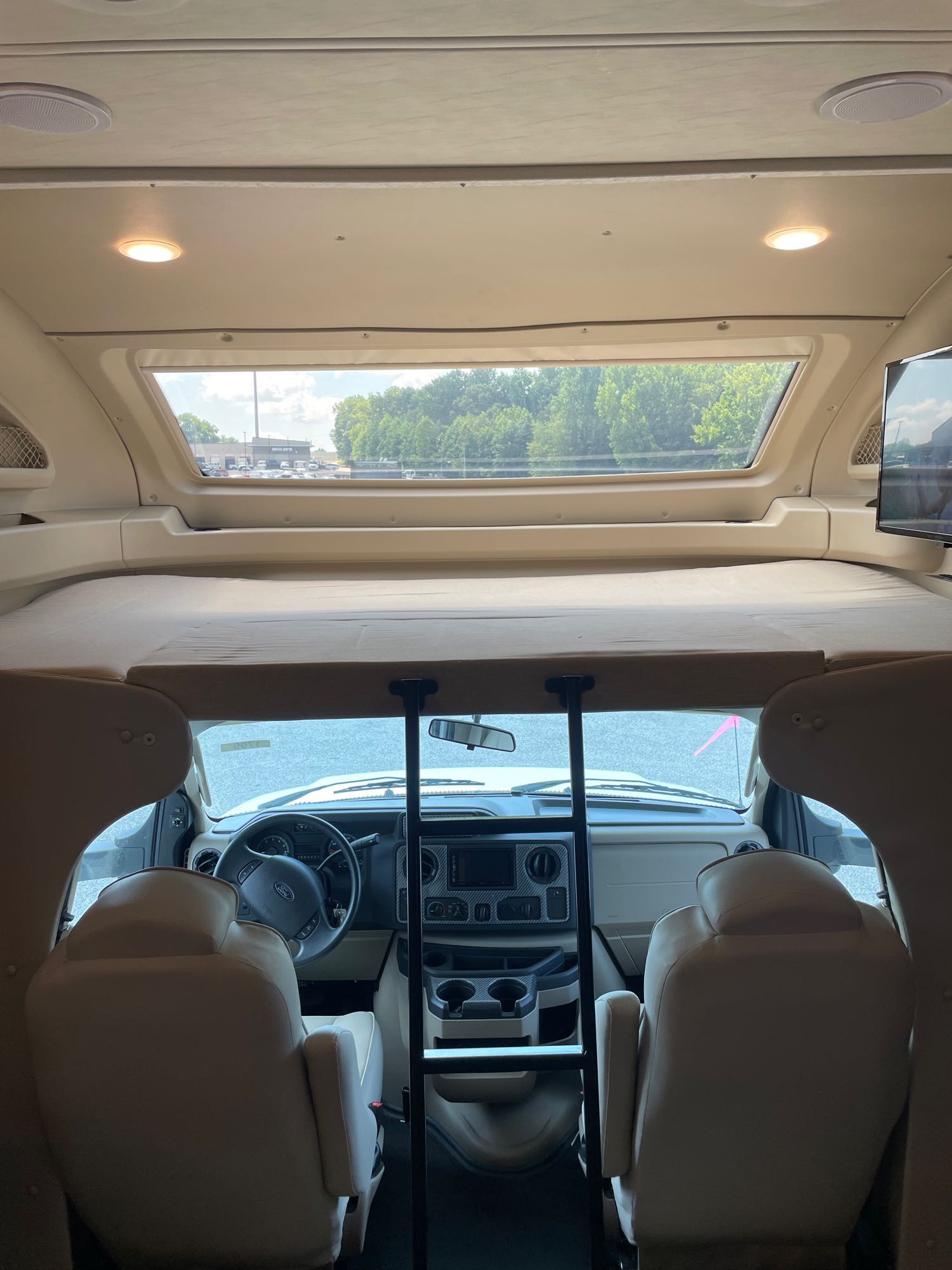 RV rental: view from inside a Class C motorhome, showing the driver's cab, overhead bunk, and front window.. Jayco Greyhawk Prestige 2020