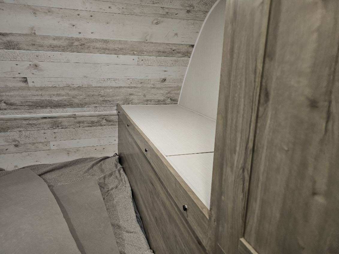 Cozy RV rental interior featuring a compact bed, wood-paneled walls, and a built-in storage bench with an arched backrest.. Forest River Puma 2024