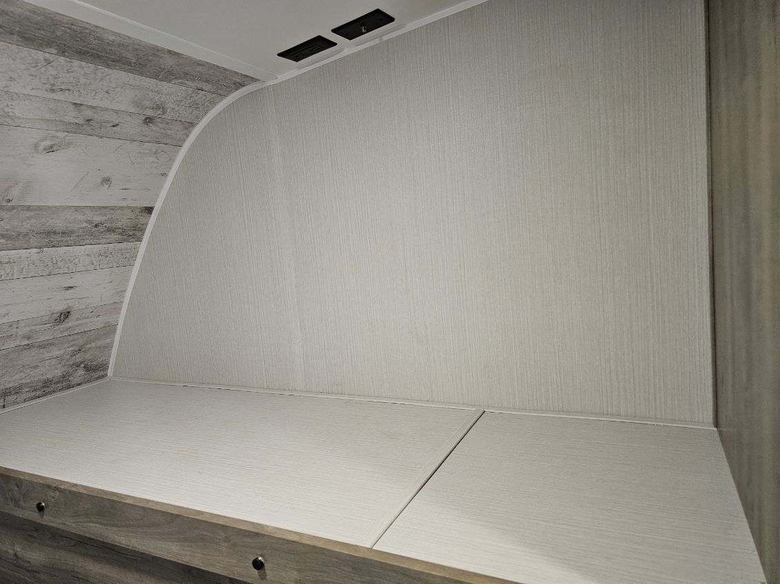 Explore a comfortable RV rental interior with a curved sleeping platform, modern wall paneling, and accessible vents.. Forest River Puma 2024