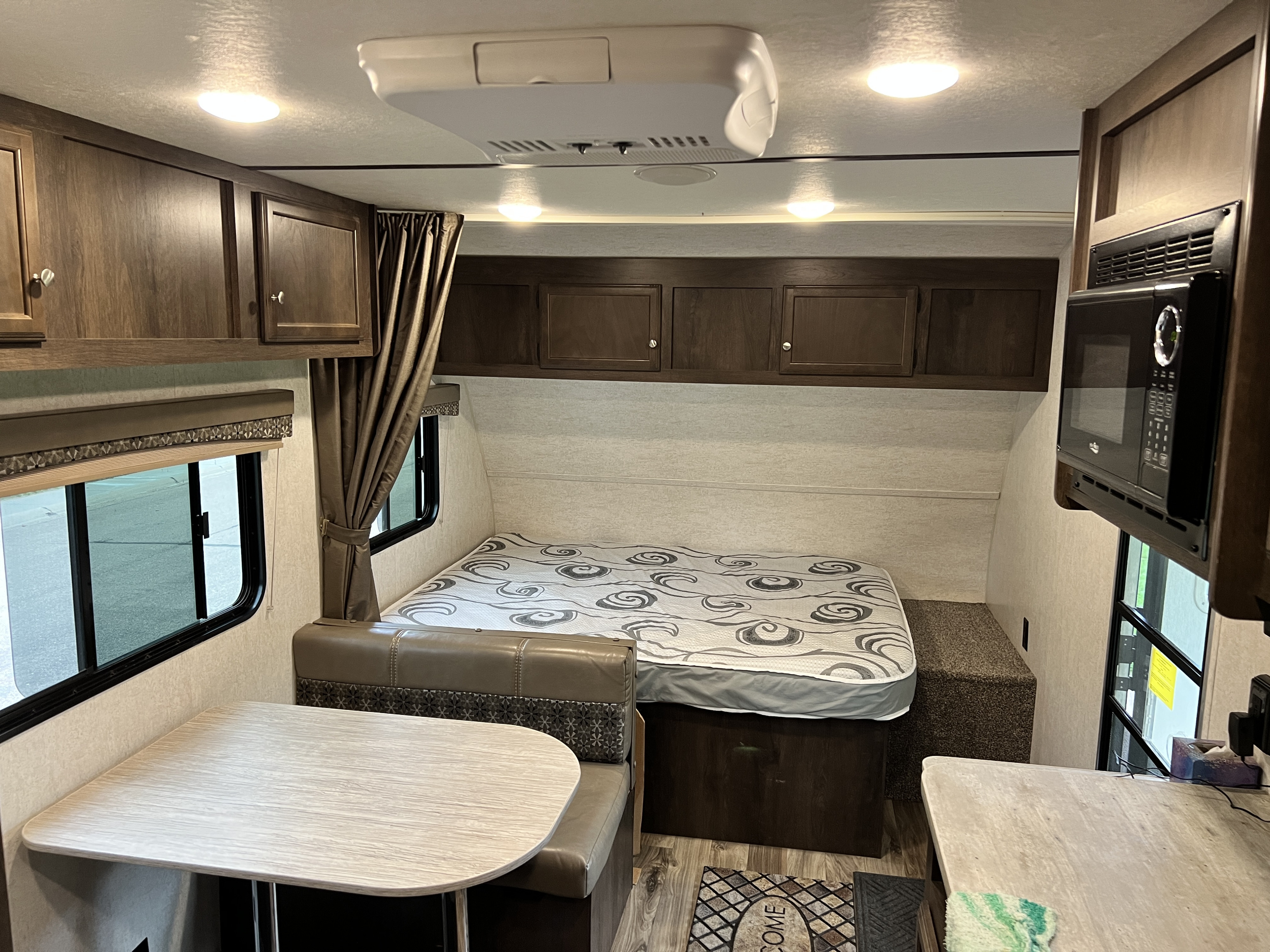 Cozy RV rental interior featuring a comfortable bed, dinette, and kitchen amenities, perfect for your next adventure.. Starcraft Autumn Ridge Outfitter 2018