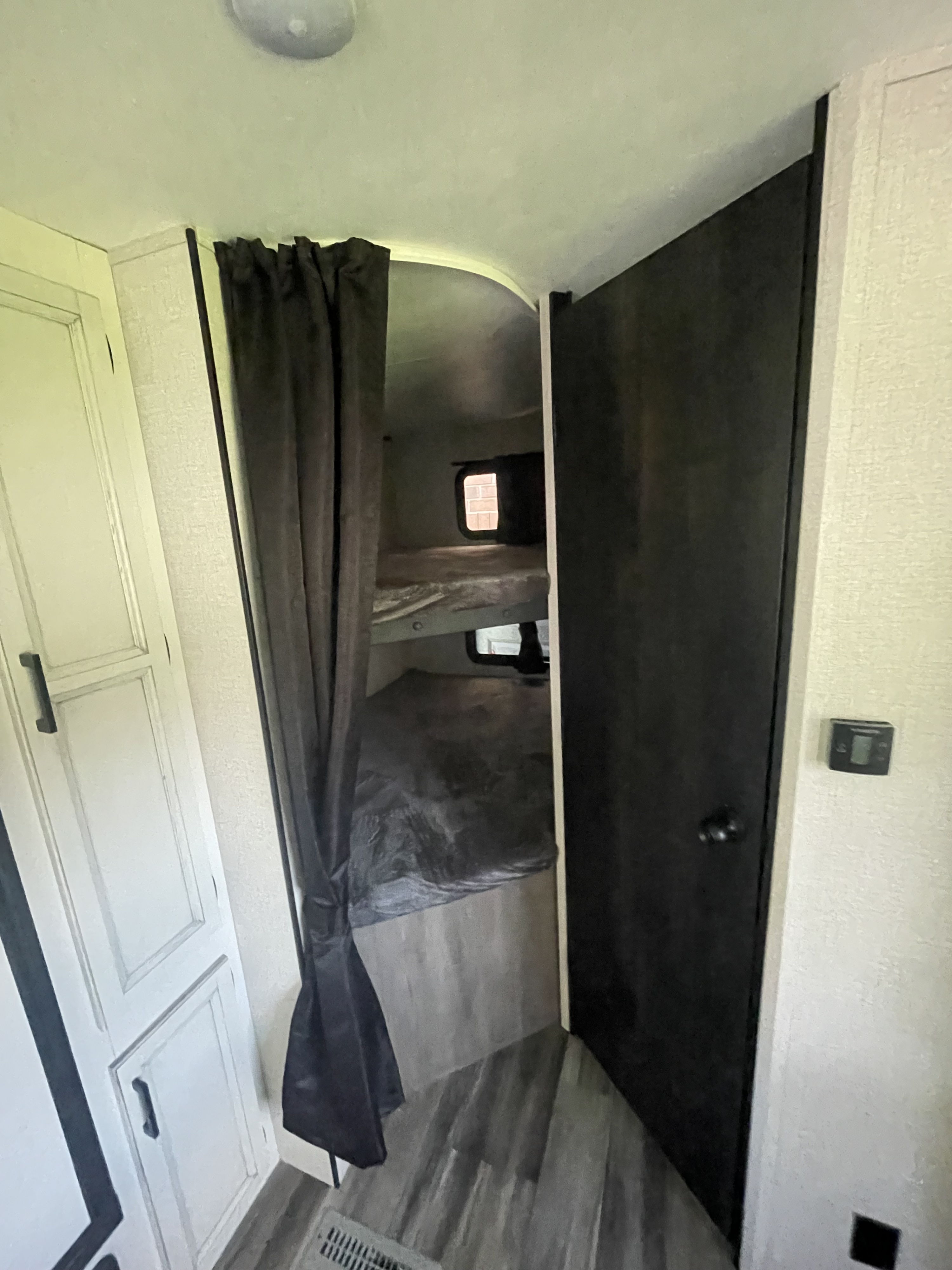 RV rental interior: Cozy bunk beds with privacy curtain, visible cabinetry and thermostat.. Highland Ridge RV Open Range 2022