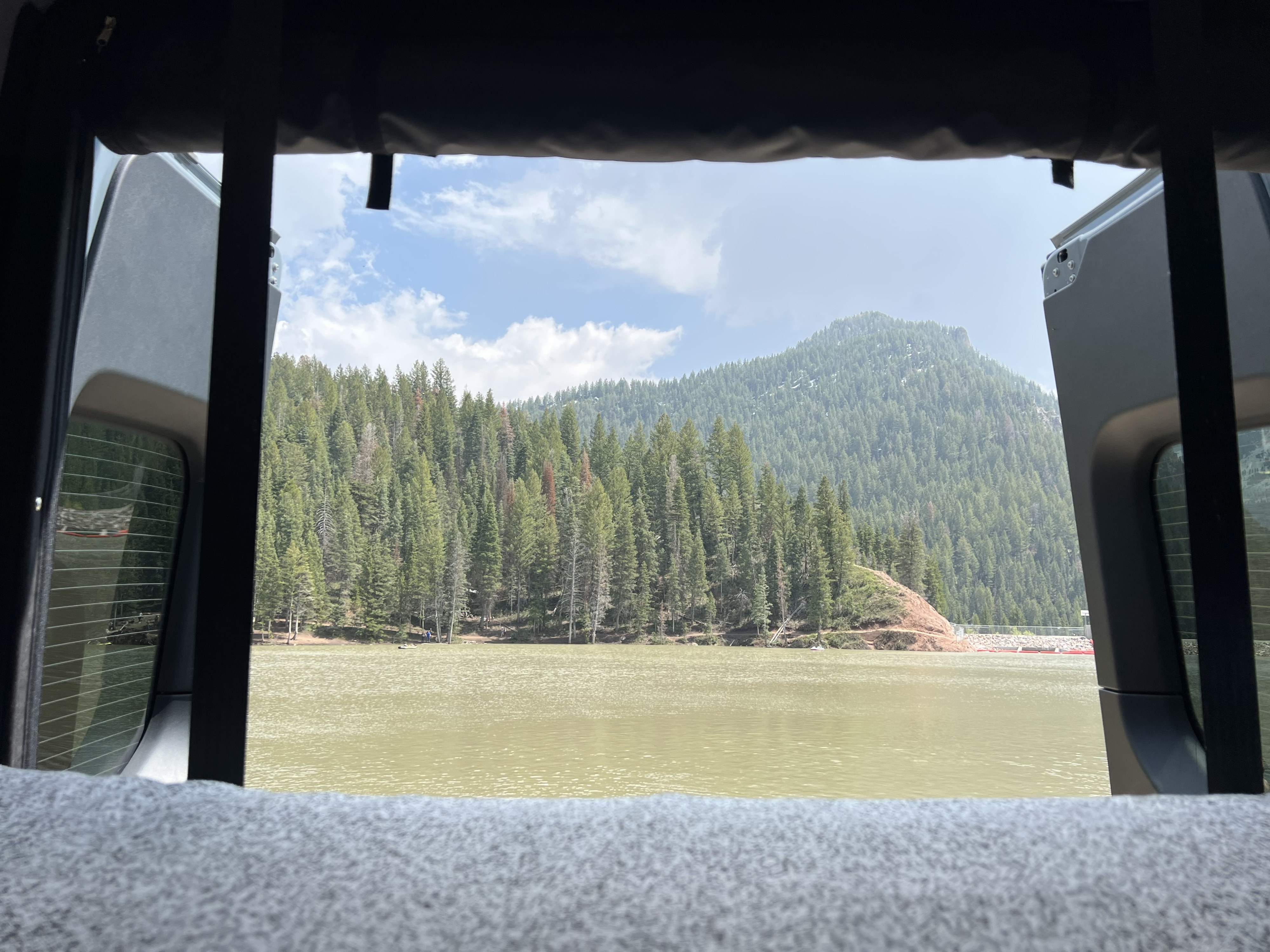Panoramic lake, forest, and mountain views from an RV rental, framed by its open rear doors.. Winnebago Revel 2023