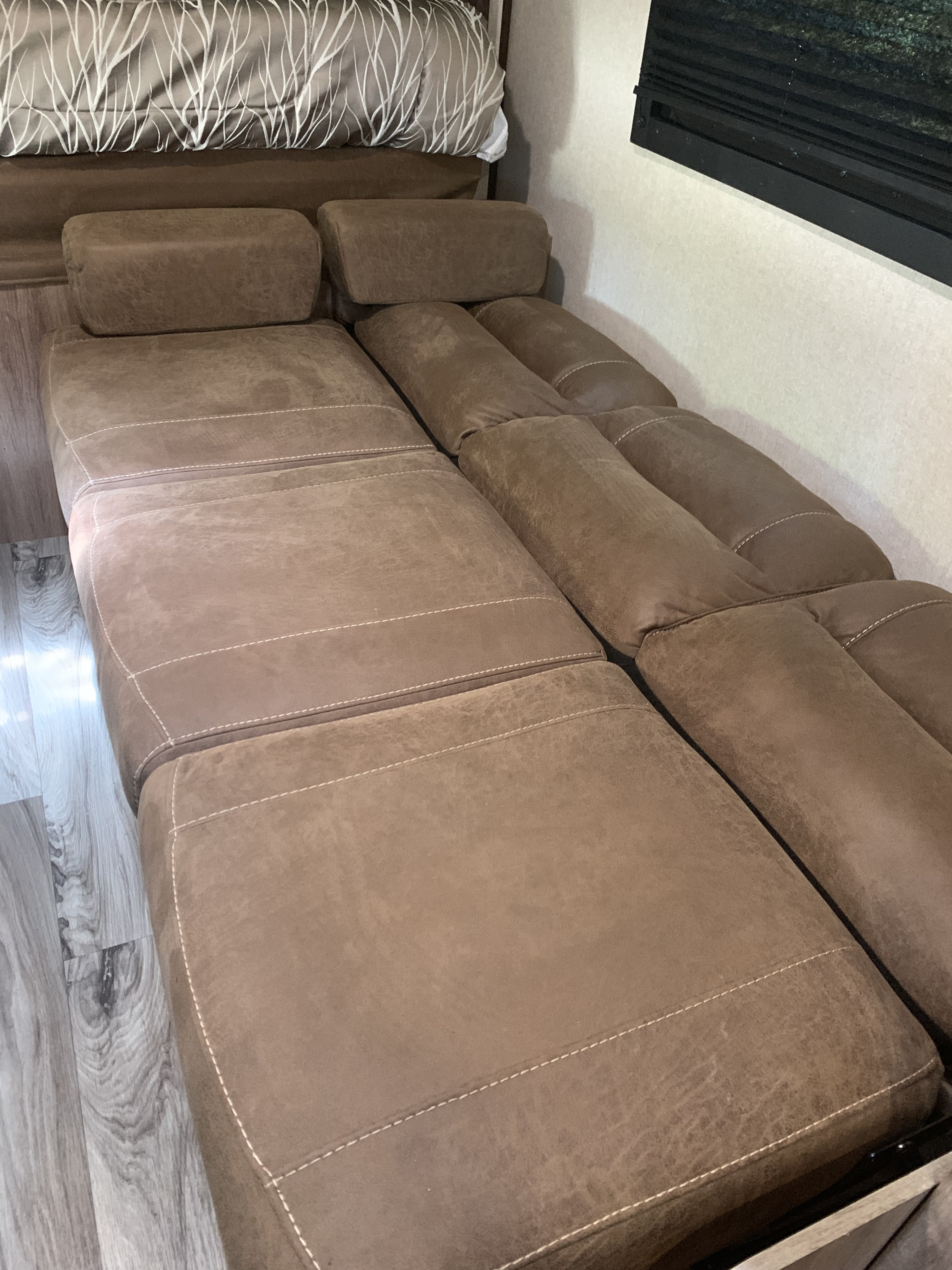 Comfortable, extended brown sofa bed inside an RV rental, perfect for relaxing or sleeping.. Jayco Jay Feather 2018