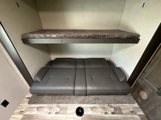 This RV rental offers a versatile sleeping area: a top bunk bed above a gray fold-out sofa bed on a wood floor.. Sport Trek Touring 2021
