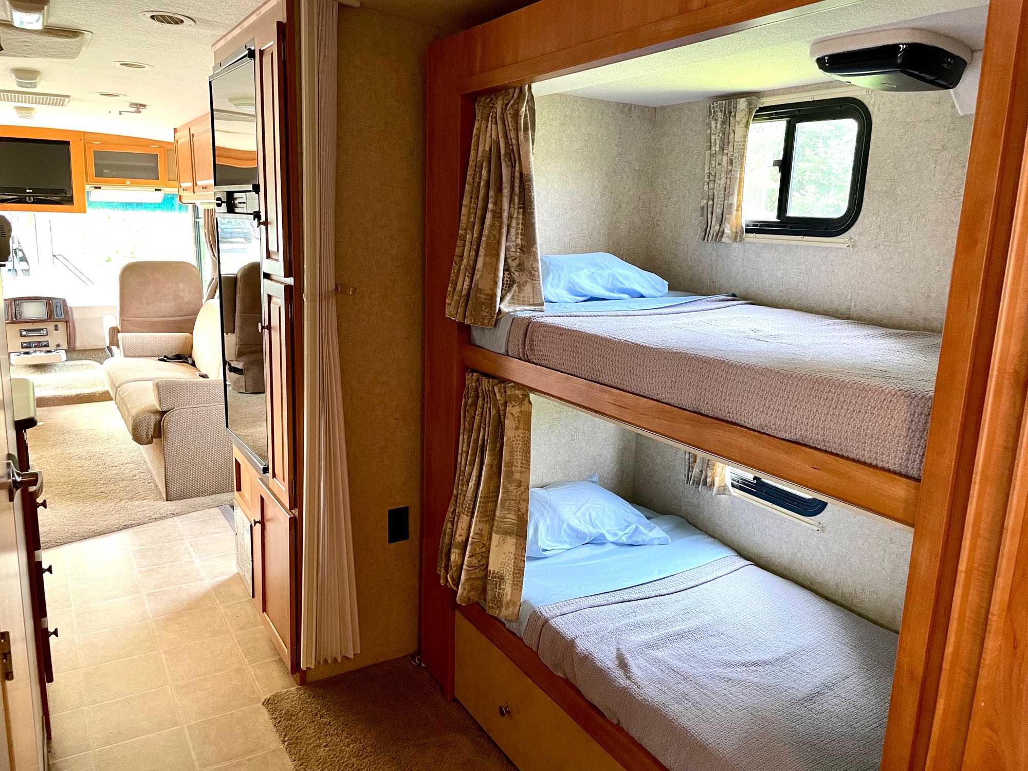 Explore this RV rental's interior, featuring comfy bunk beds and a view into the bright living area.. Itasca Sunstar 2008