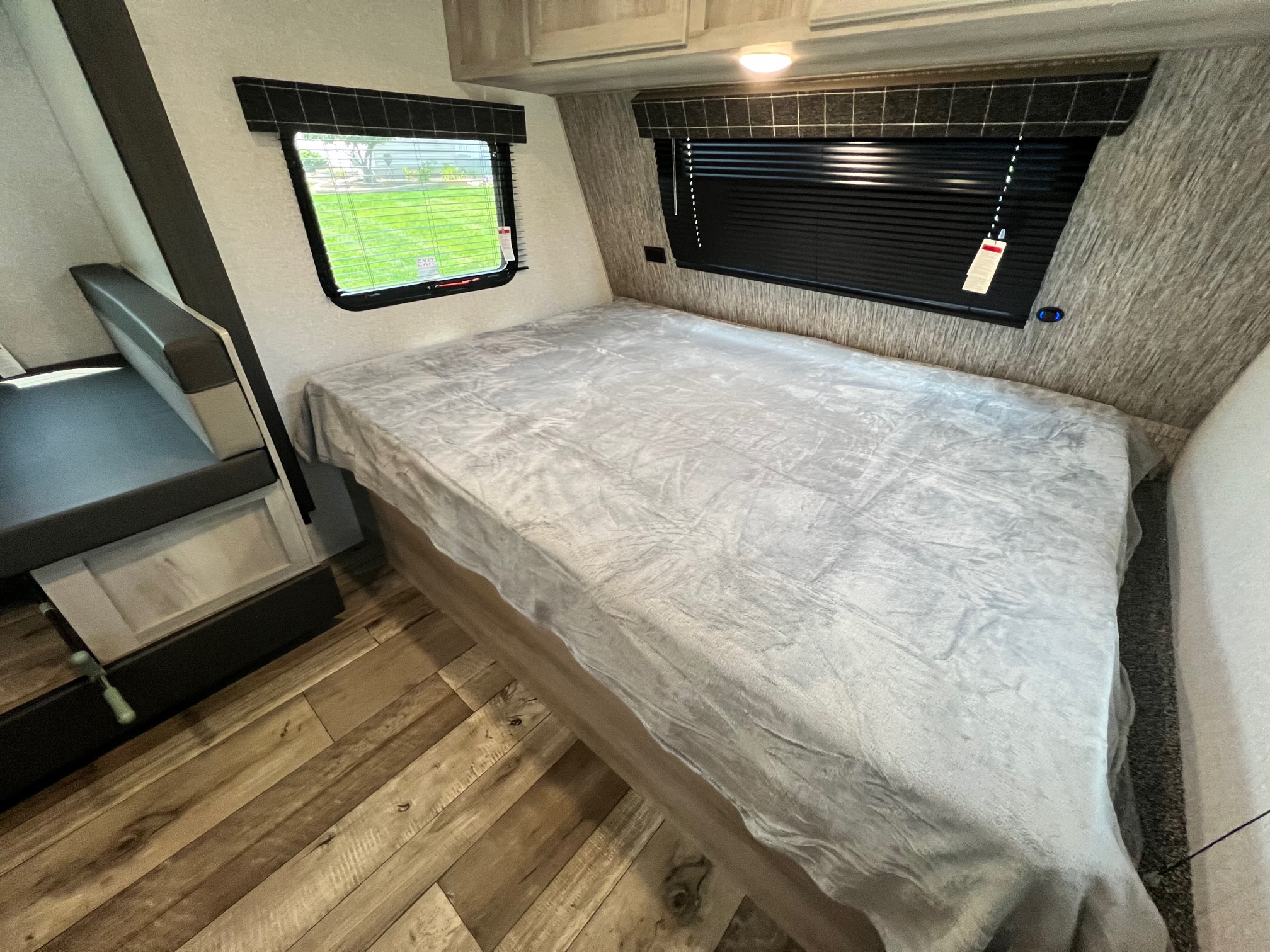 RV rental interior: bed with gray blanket, dinette seating, and bright windows. Perfect for travel.. KZ Sportsmen 191BHK 2022