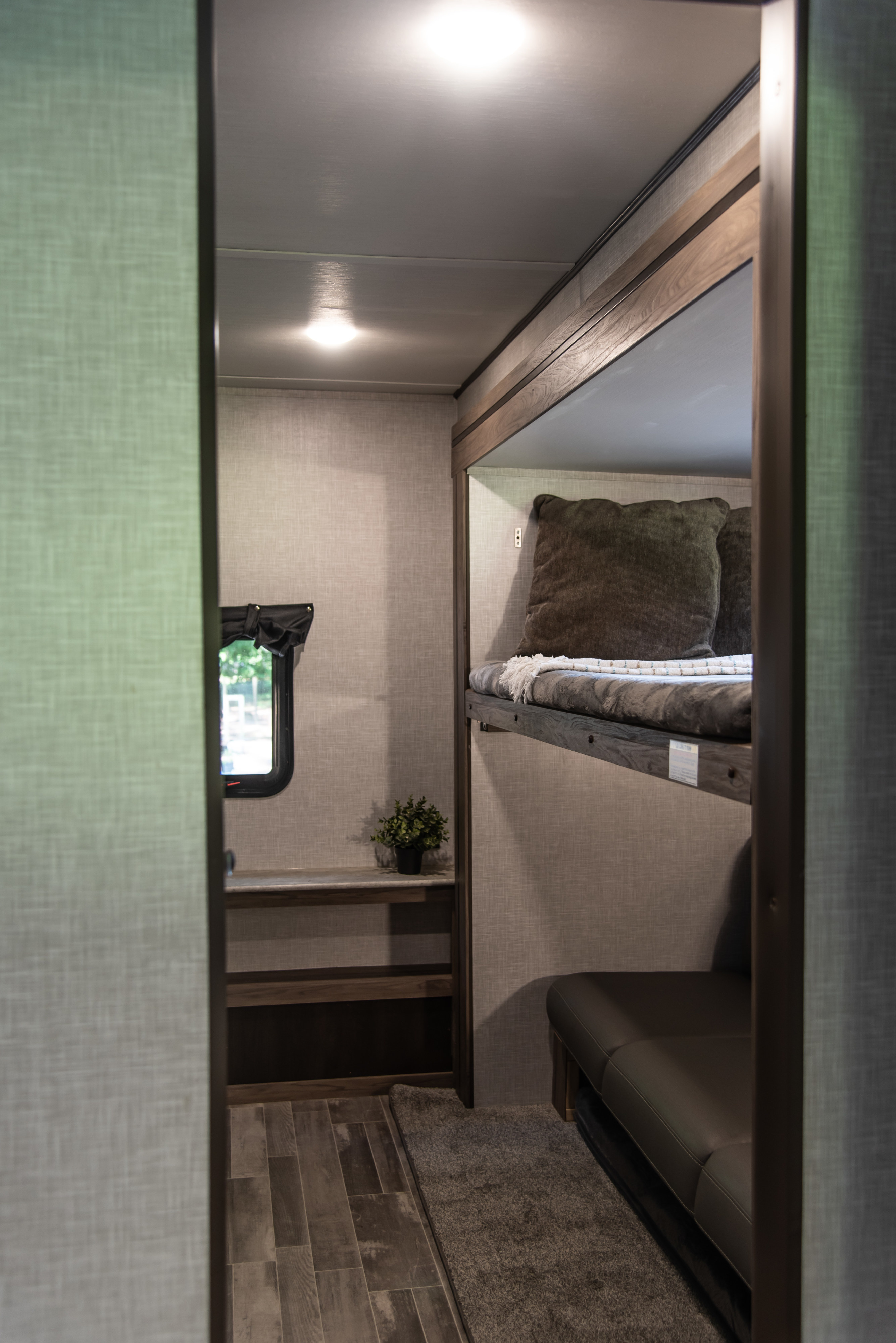 This RV rental's bunk area offers cozy beds, a sofa, and shelves. Experience a functional and comfortable space for travel.. Crossroads RV Zinger 2023