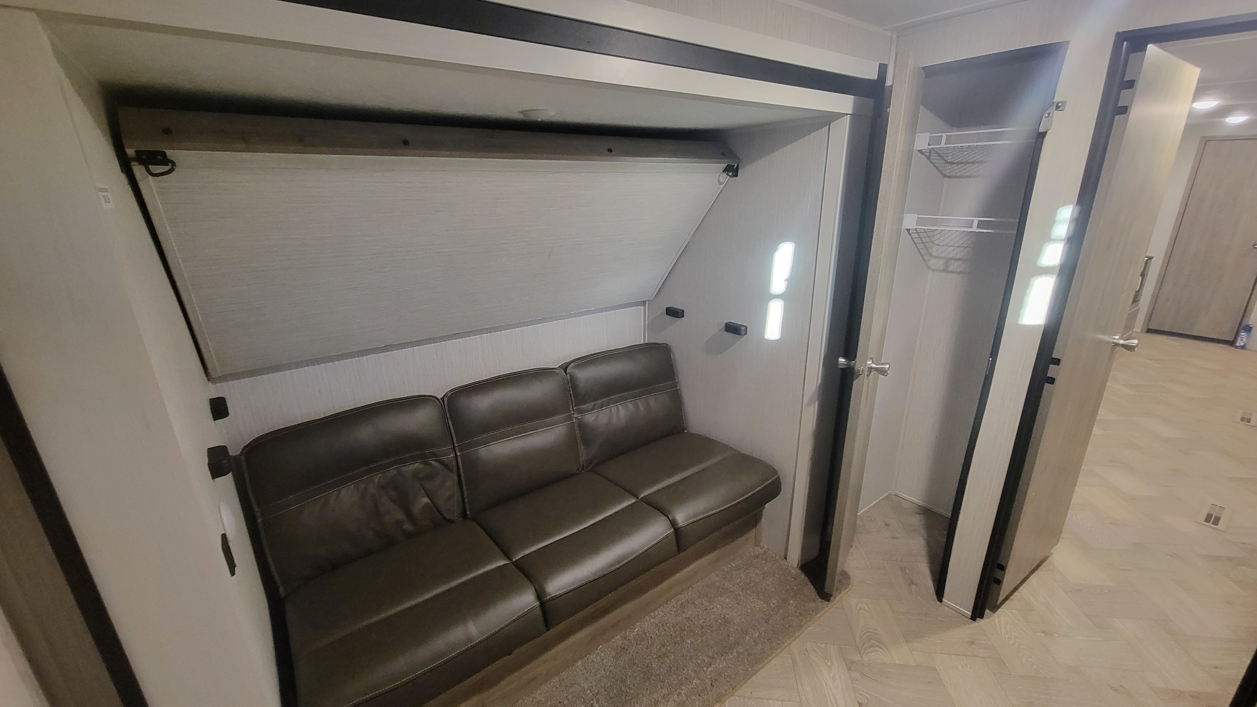 Modern RV rental interior with a comfortable couch, potential murphy bed area above, and built-in storage. Ideal for trips.. Forest River Palomino Puma 2021