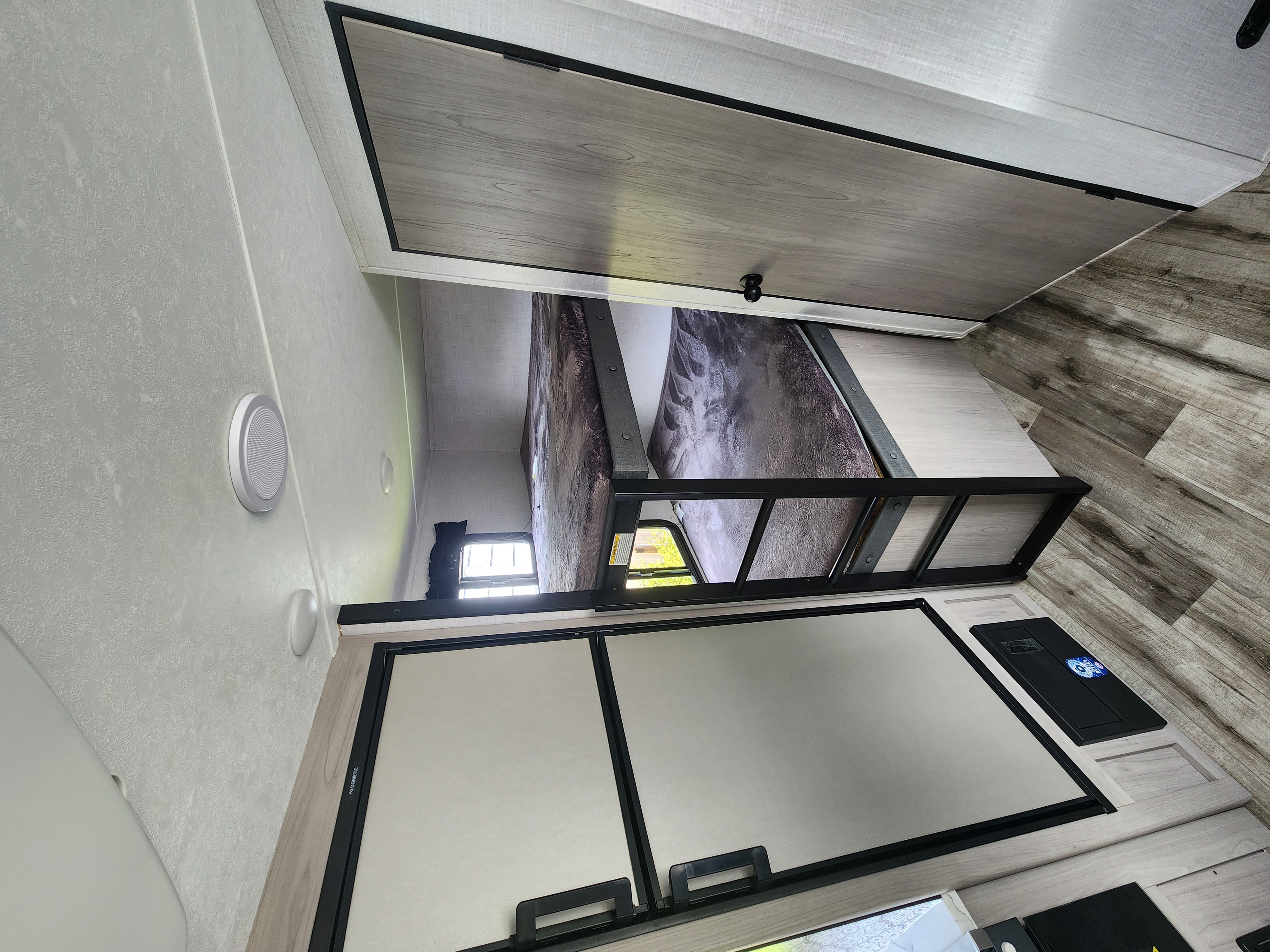 Inside an RV rental, featuring stacked bunk beds, a Dometic refrigerator, and clean, light interior finishes.. Dutchmen Coleman Light 2022