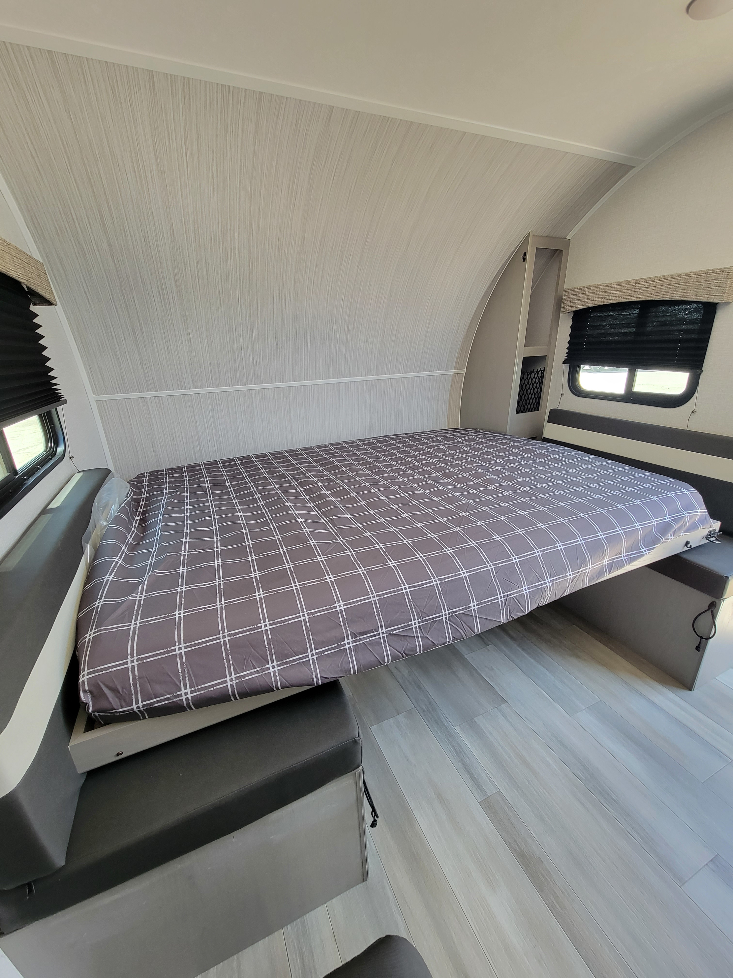 RV rental: A grey plaid murphy bed extends over a dinette bench in a compact RV interior, optimizing space.. Viking 18SBH 2023