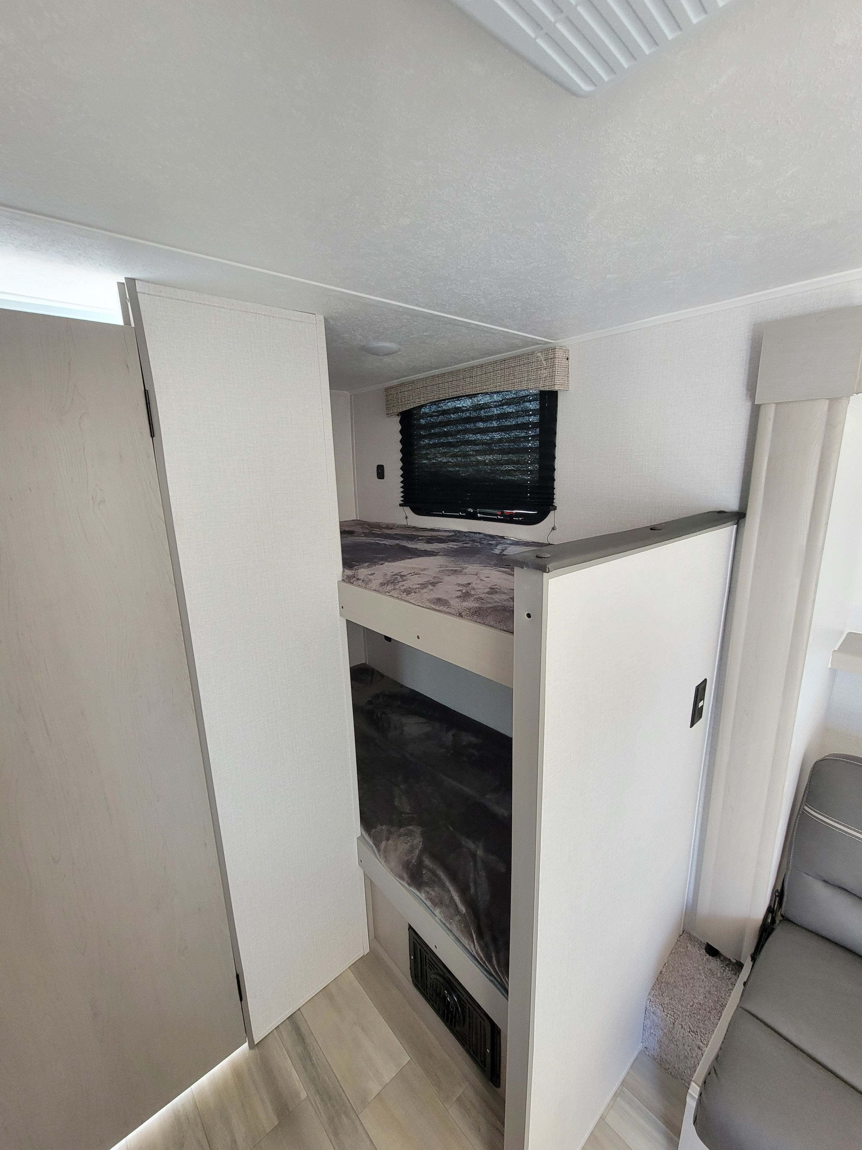 Inside this RV rental, comfortable bunk beds offer a compact sleeping area with a window, perfect for family travel.. Viking 18SBH 2023