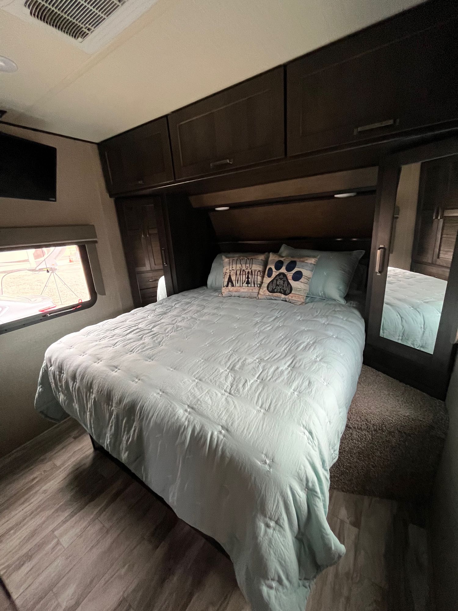 Cozy RV rental bedroom with a queen bed, overhead storage, and TV, ready for your next camping trip.. Grand Design Reflection 2022