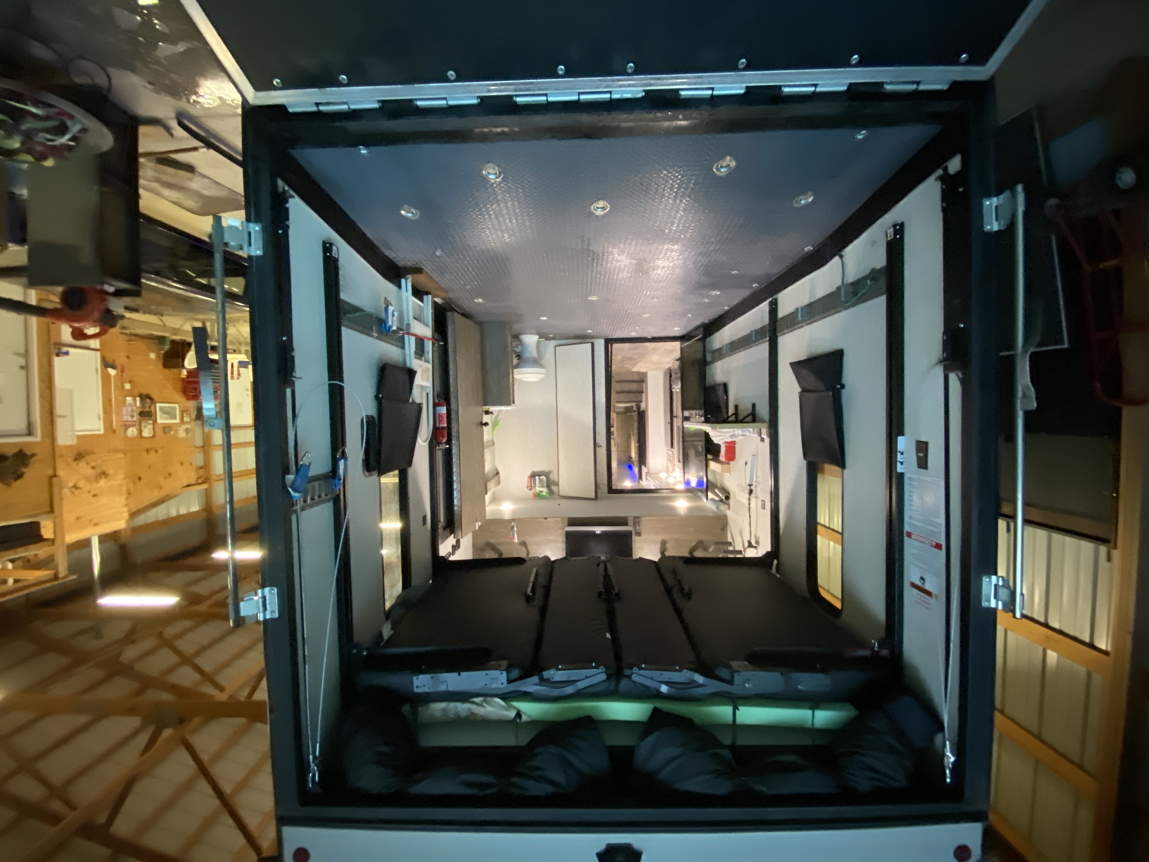 Inside an **rv rental**, a versatile toy hauler interior is revealed through the open rear ramp, featuring multiple convertible beds and a living area.. Forest River Wolf Pack 2020