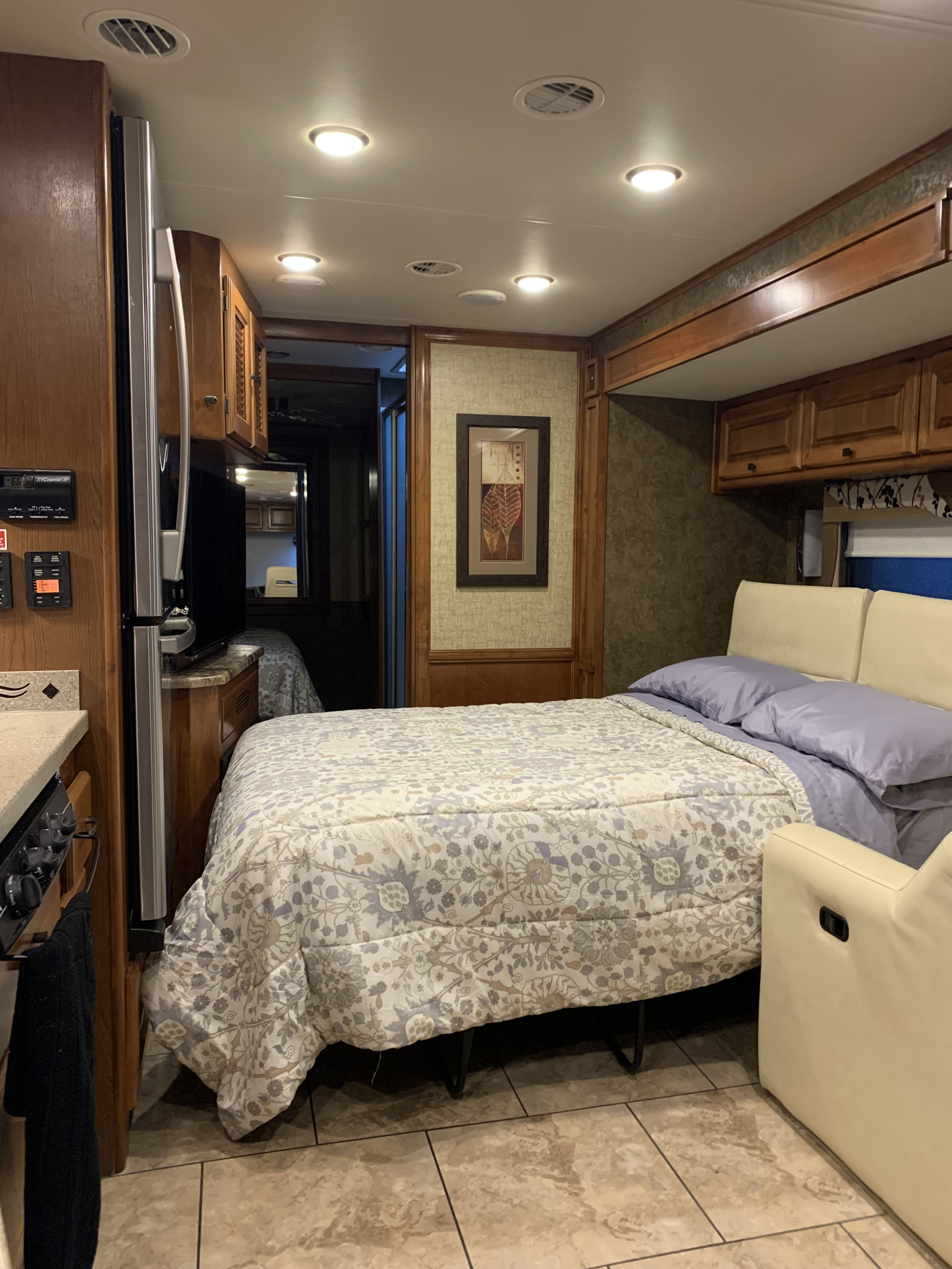 Cozy RV rental interior with fold-out bed, cream recliners, kitchen area, fridge, wood cabinets, and tiled floors.. Allegro Allegro Motorhome 2014