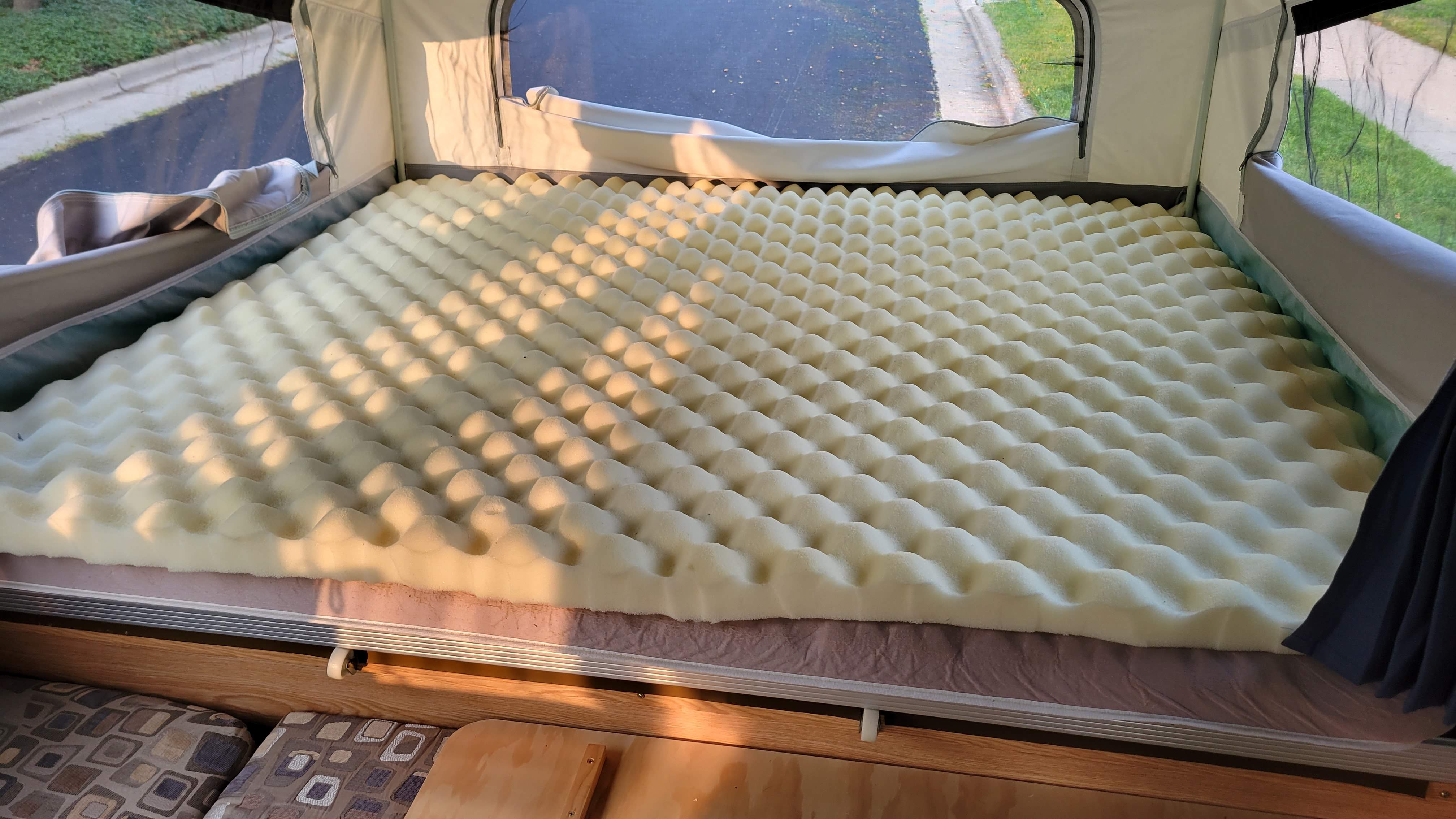 Enhance your RV rental comfort: A large egg crate foam mattress topper fills a camper bed, bathed in sunlight.. Forest River Palomino 2011
