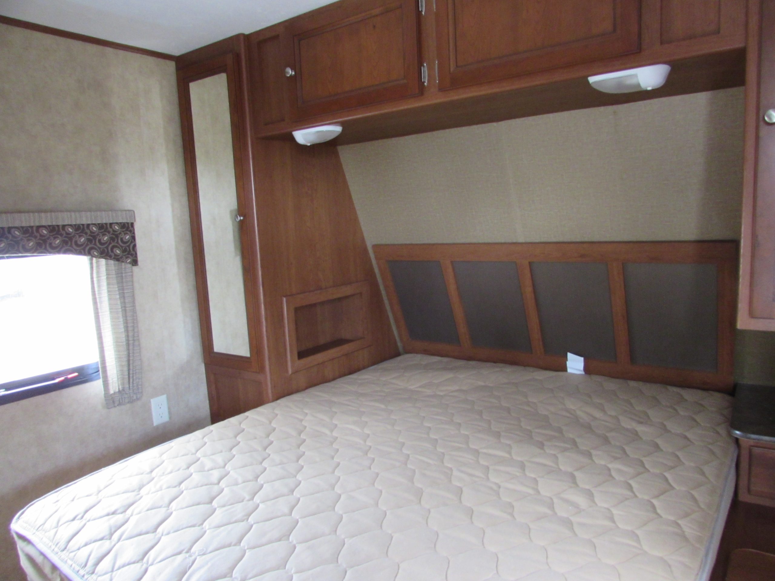 Queen bed with closet space on both sides, cabinets above.. Dutchmen Coleman Expedition LT 2013