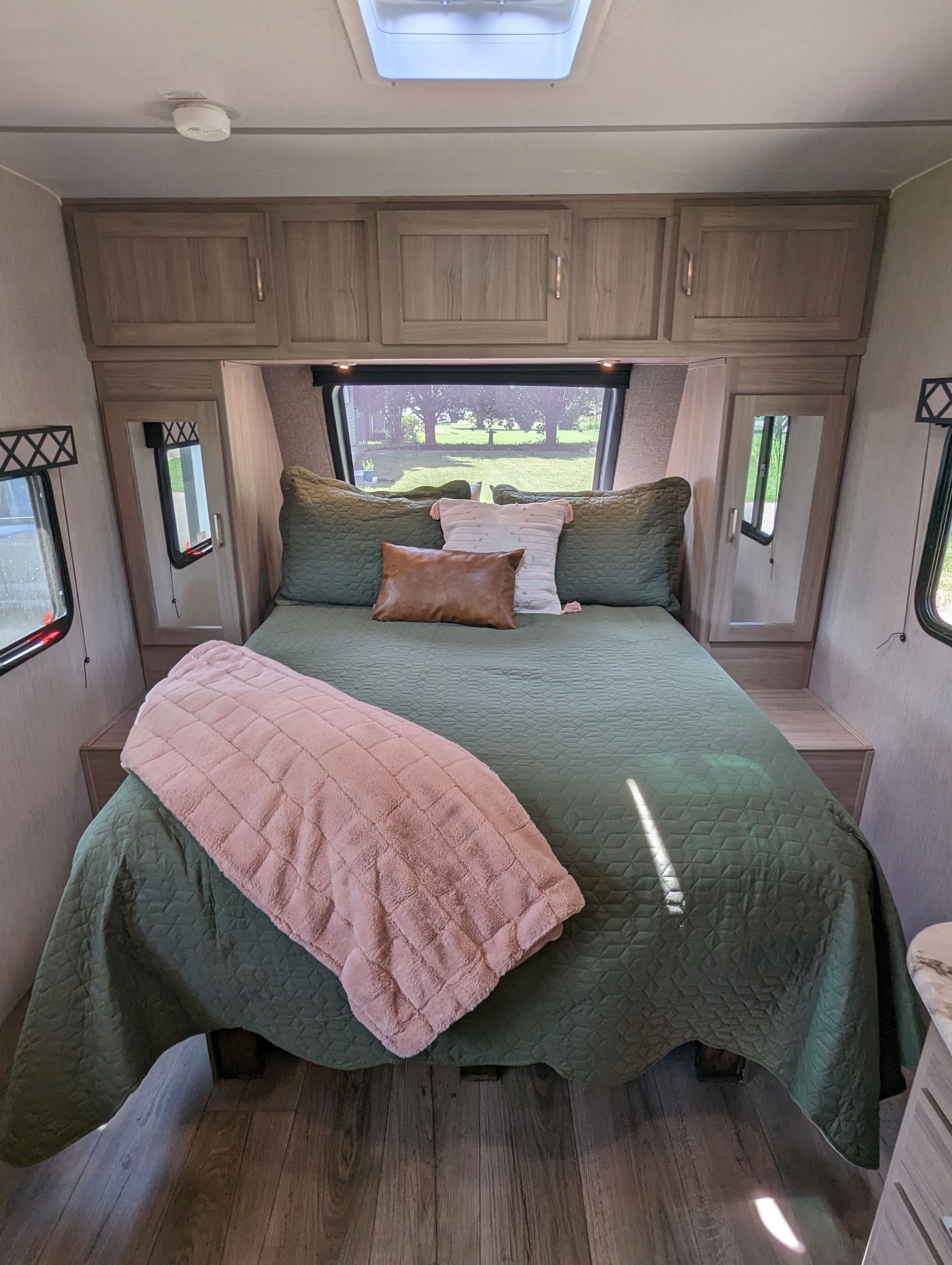 Step into comfort! This inviting RV rental bedroom features a green bed, ample storage, and scenic window views.. Forest River Coachmen Freedom Express Ultra Lite 2020