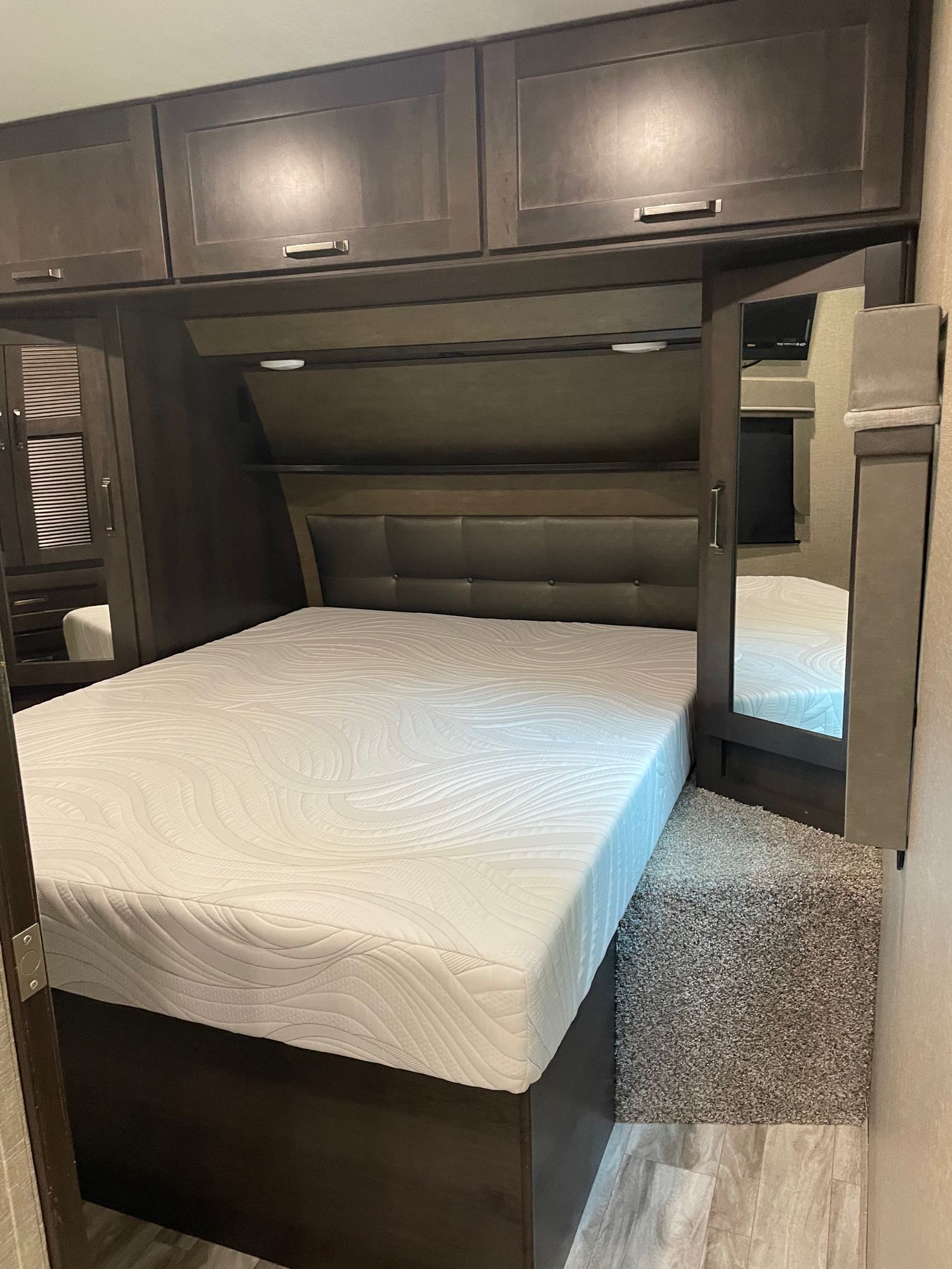 Well-appointed RV rental bedroom with large bed, built-in storage, and mirrored closet for comfortable travel.. Grand Design Reflection 2022