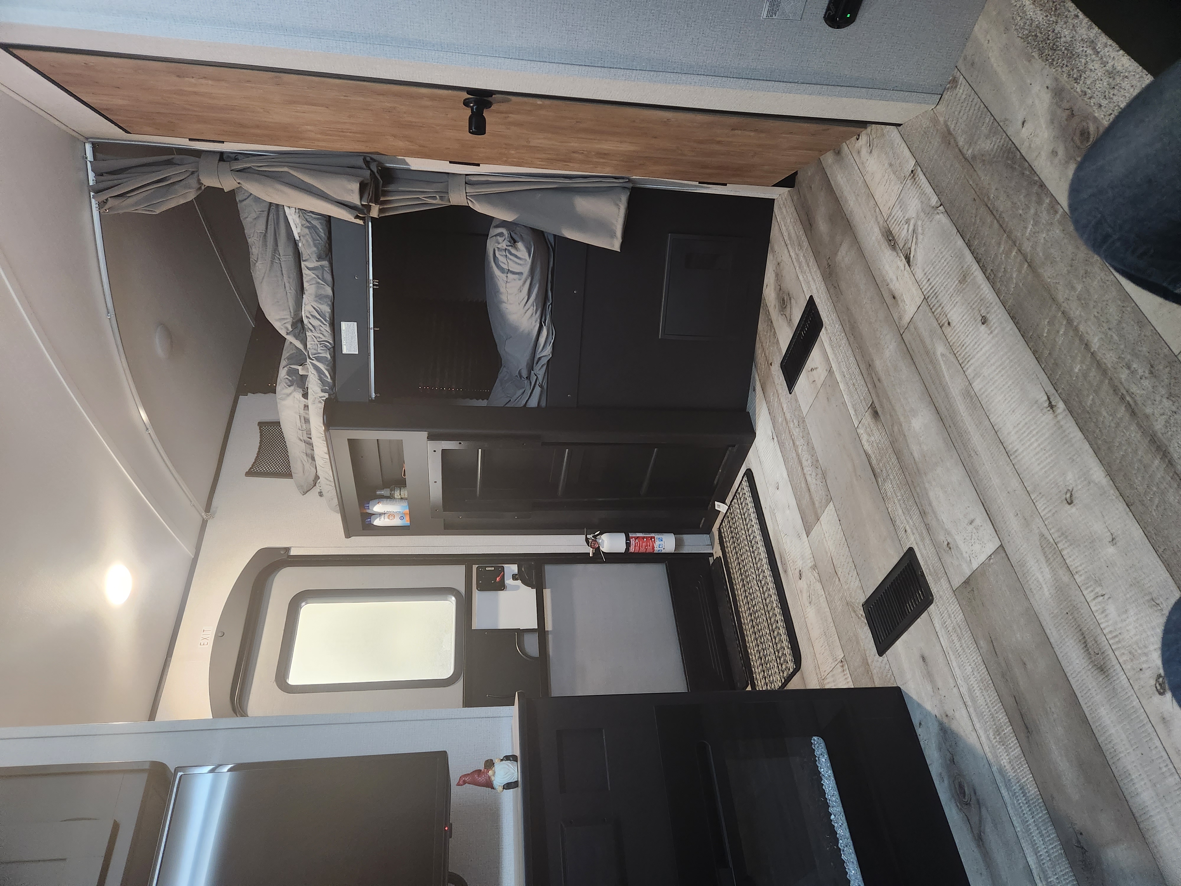 RV rental interior view: bunk beds with privacy curtains, wood-look flooring, and a safety fire extinguisher.. Keystone RV Springdale 2022
