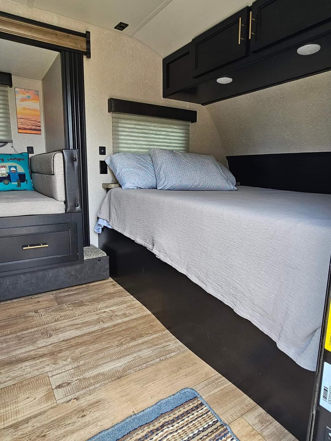 Inside a comfortable RV rental: A well-appointed bedroom with overhead storage, adjacent to a cozy dinette.. Forest River Cherokee Wolf Pup Black Label 2021