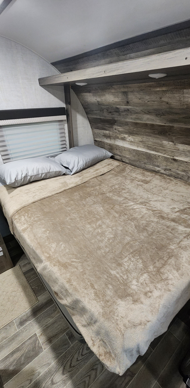 Cozy RV rental bedroom featuring a comfy bed, modern wood paneling, and a window for natural light.. Gulf Stream Conquest Super Lite 2021