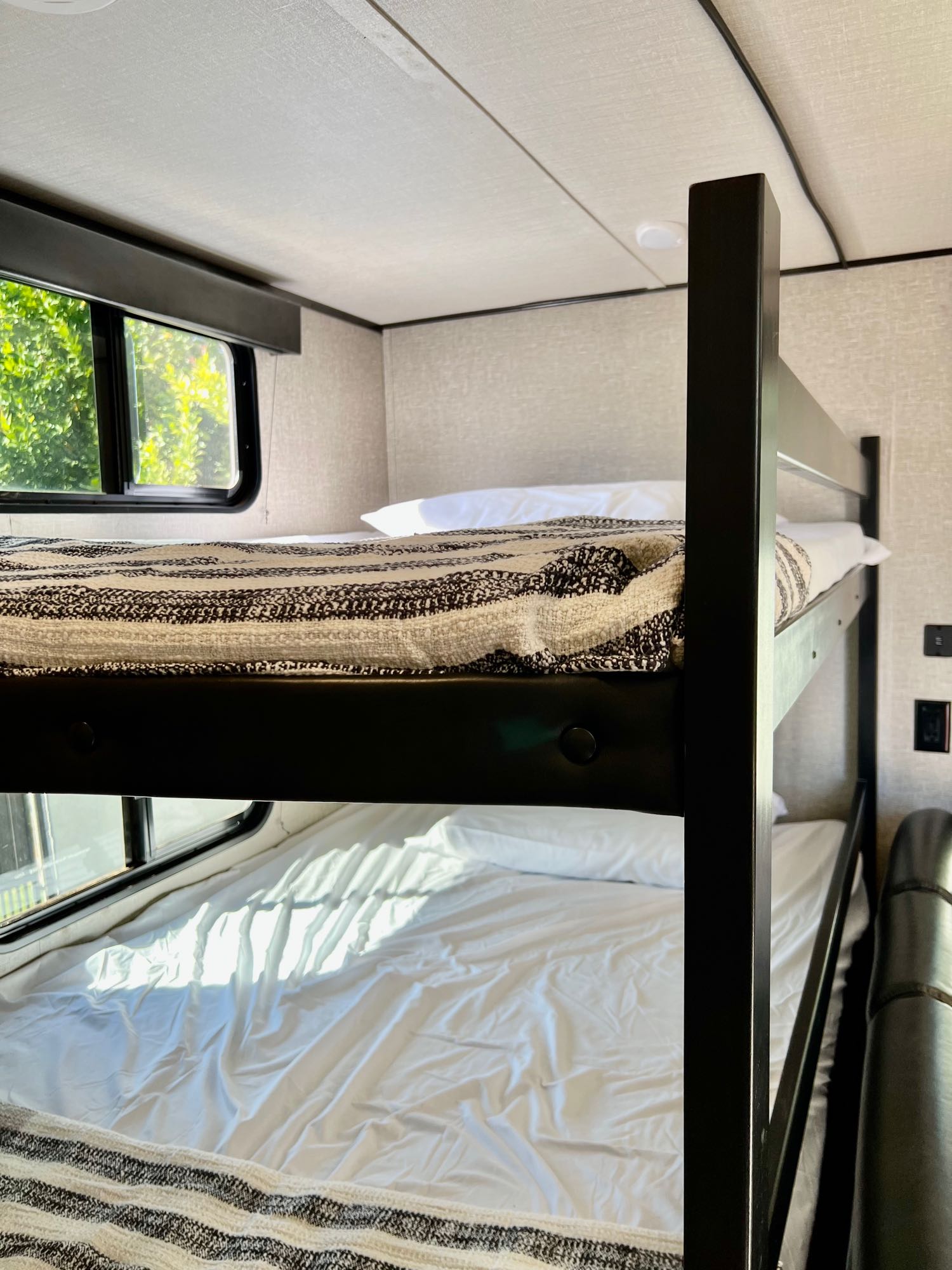Cozy bunk beds in an RV rental, with white sheets & blankets. Windows let in natural light, perfect for travels.. Grand Design Transcend Xplor 2020