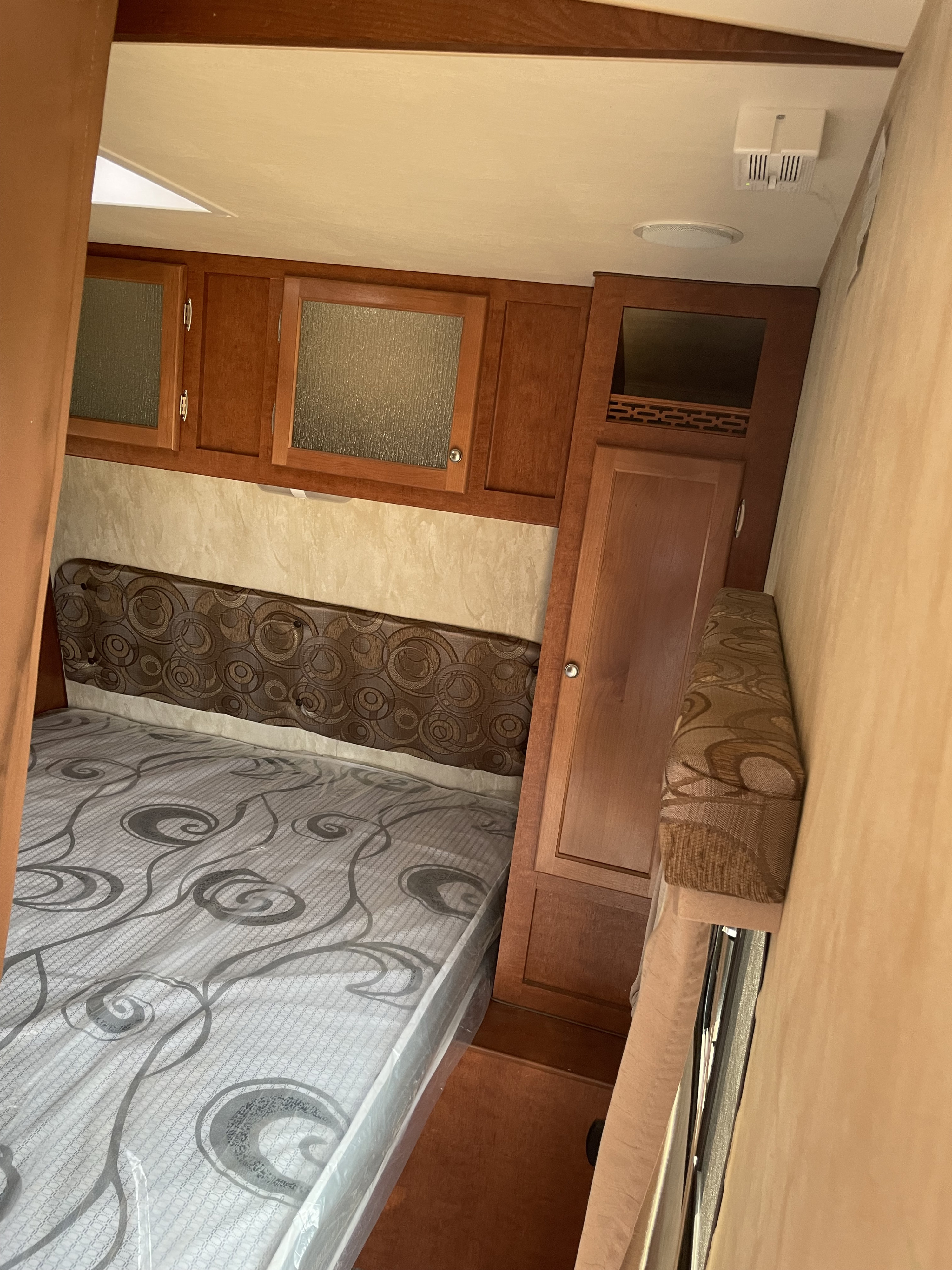 Explore this RV rental's bedroom: new mattress, patterned headboard, wood cabinets, and built-in storage.. Nash Nash Trailer 2018